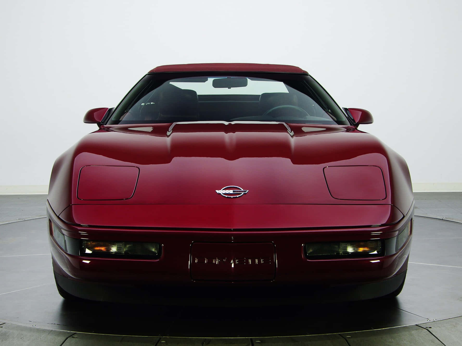 工作室中的栗色Corvette跑車，地板反光，牆壁白色。
