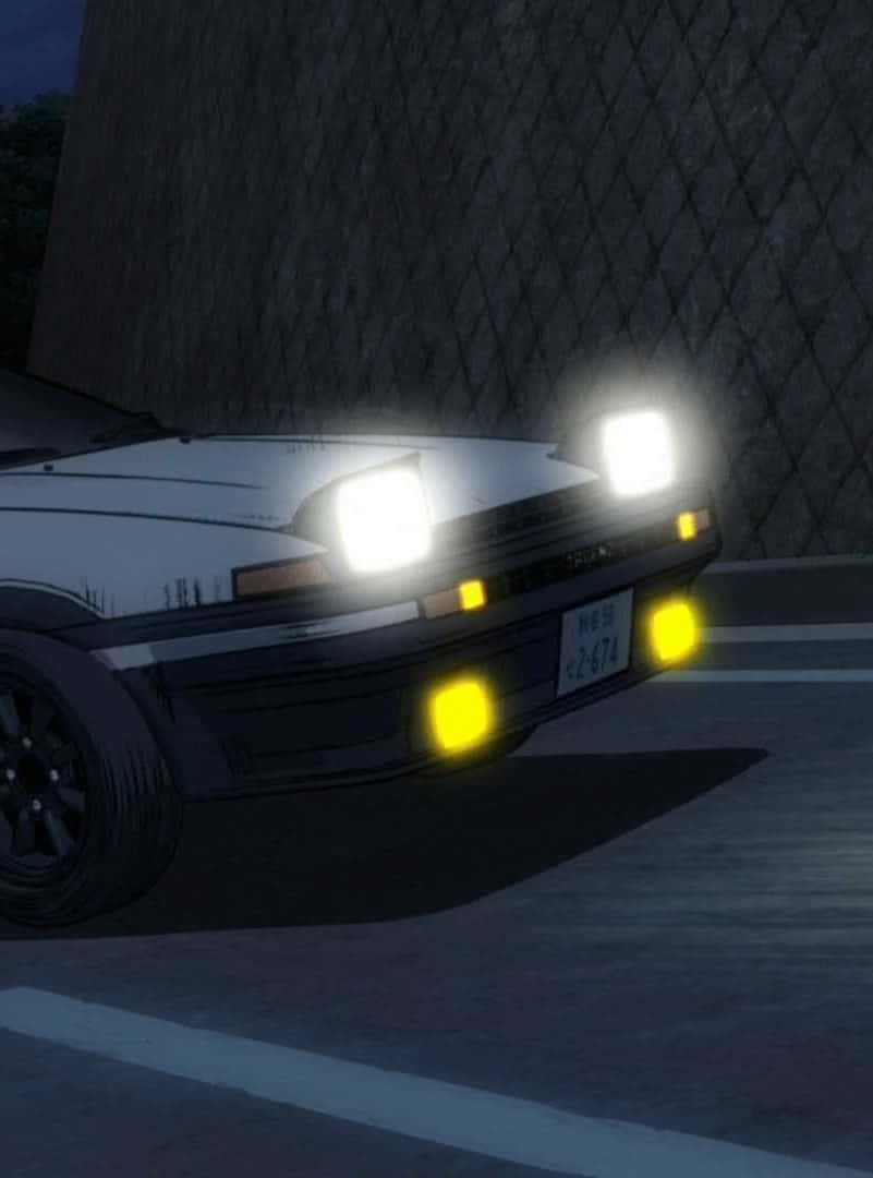 白色跑車，頭燈明亮，夜間停放在圍欄附近。