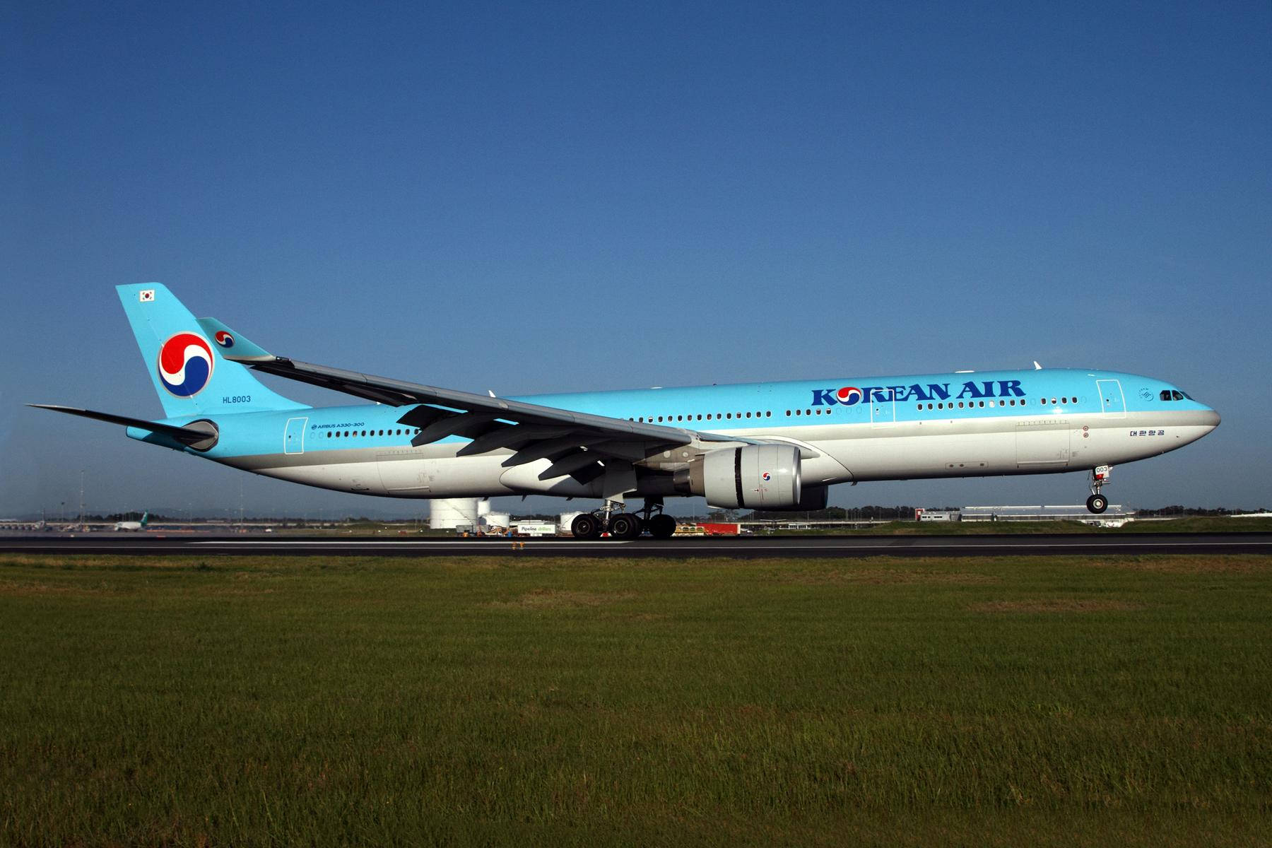 大韓航空飛機喺跑道，有綠色草地同晴朗藍天。