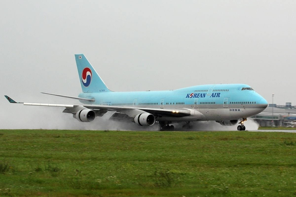 大韓航空波音747在潮濕跑道上降落，附近有草地。