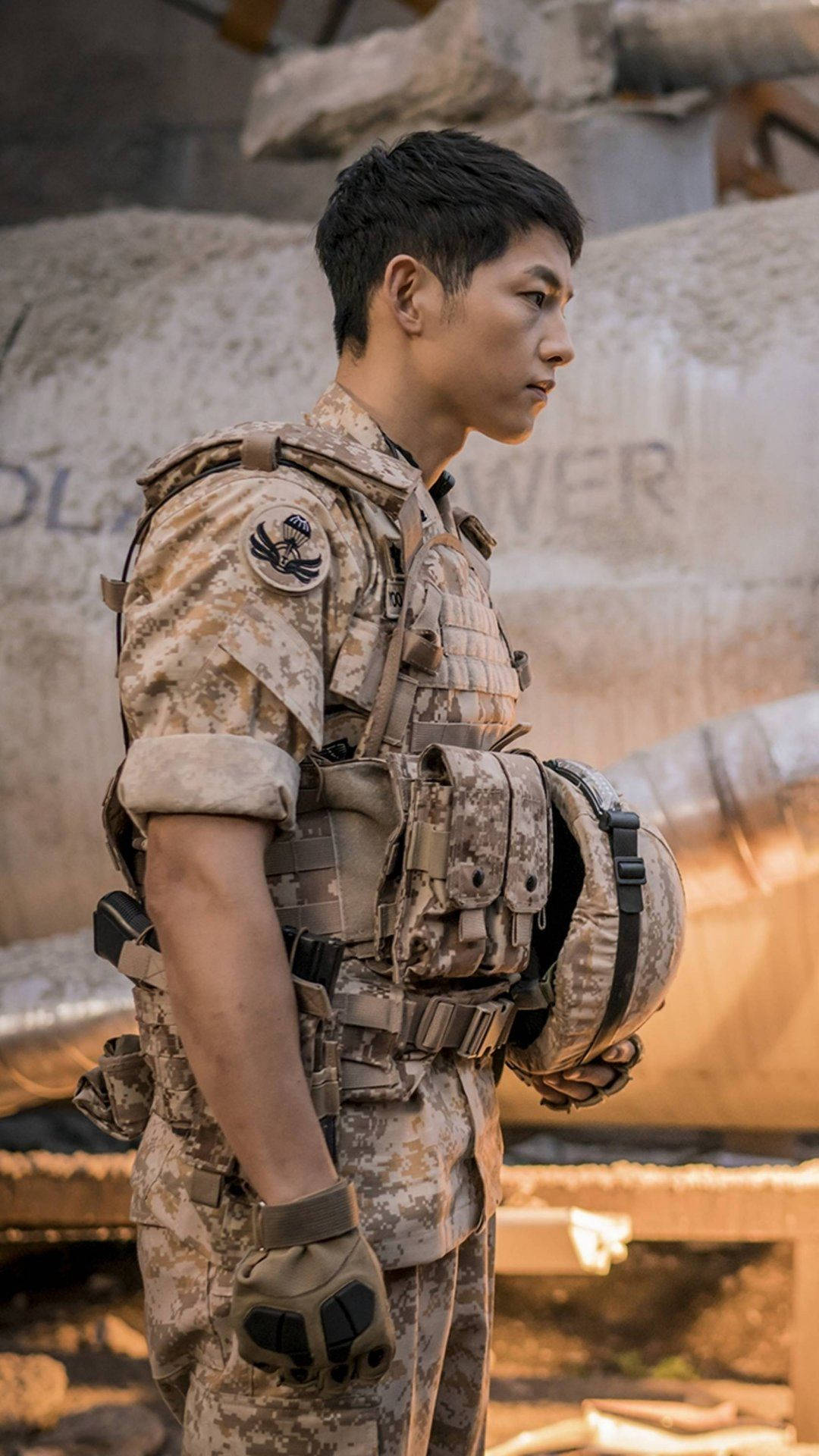 一名全副武裝的士兵站在被毀的城市環境中，旁邊是一輛生鏽的坦克。