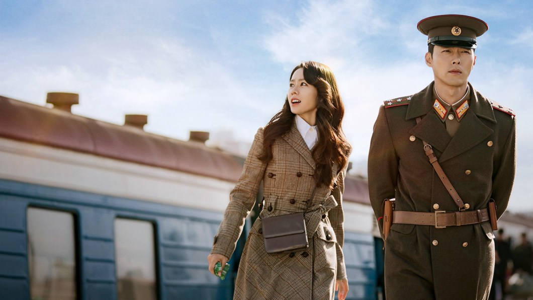 女人和士兵在日落時分站在火車附近。