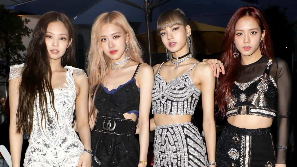 韓國女團 BLACKPINK 成員合照 壁紙 — 四位華麗的K-pop偶像在晚燈下自信地擺姿勢，身穿閃亮的黑白服裝。