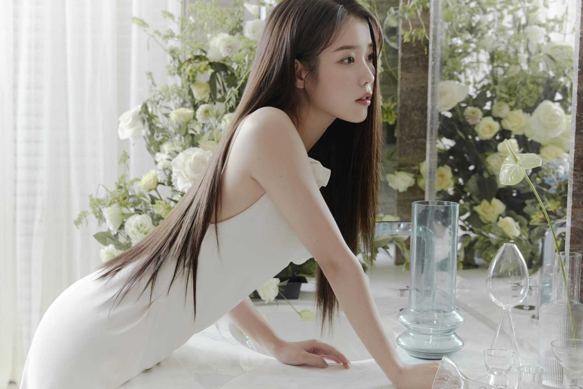 身穿白色連衣裙的女性俯身於帶有花卉裝飾的桌子上。