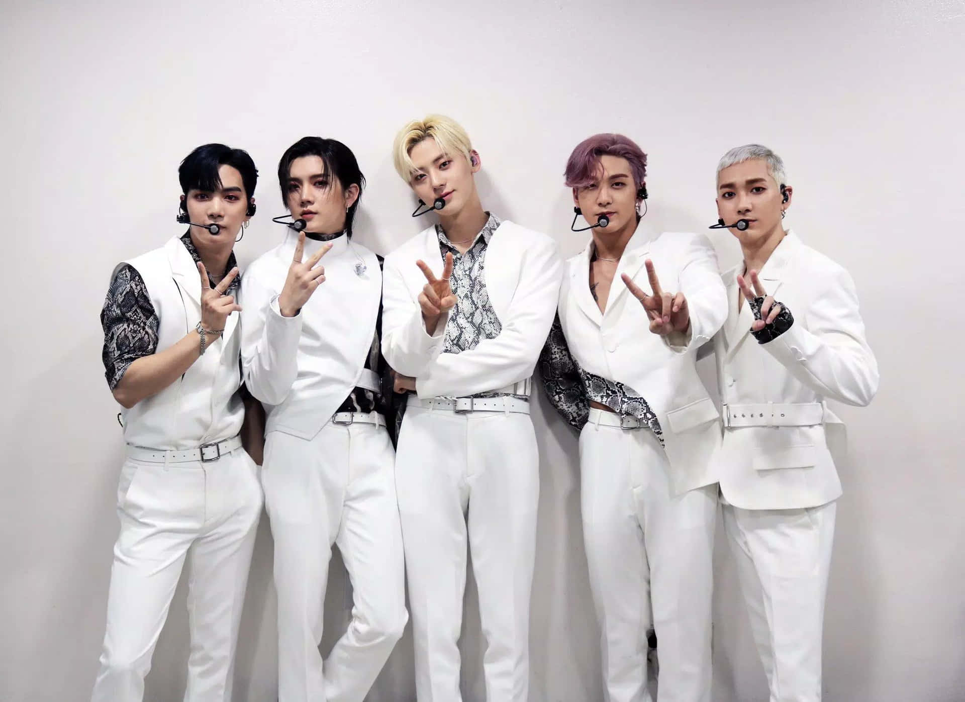 韓國流行樂壇的耀眼明星 NU'EST，展現魅力與才華 壁紙 — 五位時尚的K-pop偶像身穿白色西裝配圖案襯衫，自信地靠著素牆擺姿勢，做出和平手勢。