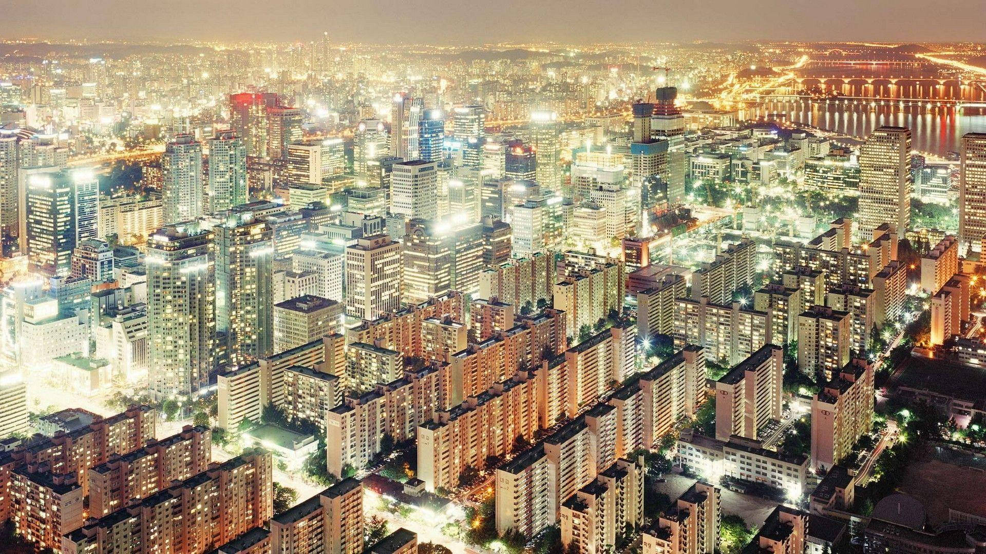 韓國璀璨夜景 壁紙 — 俯瞰一個在夜間蔓延的城市，閃爍的摩天大樓和住宅區被溫暖的人造燈光照亮。
