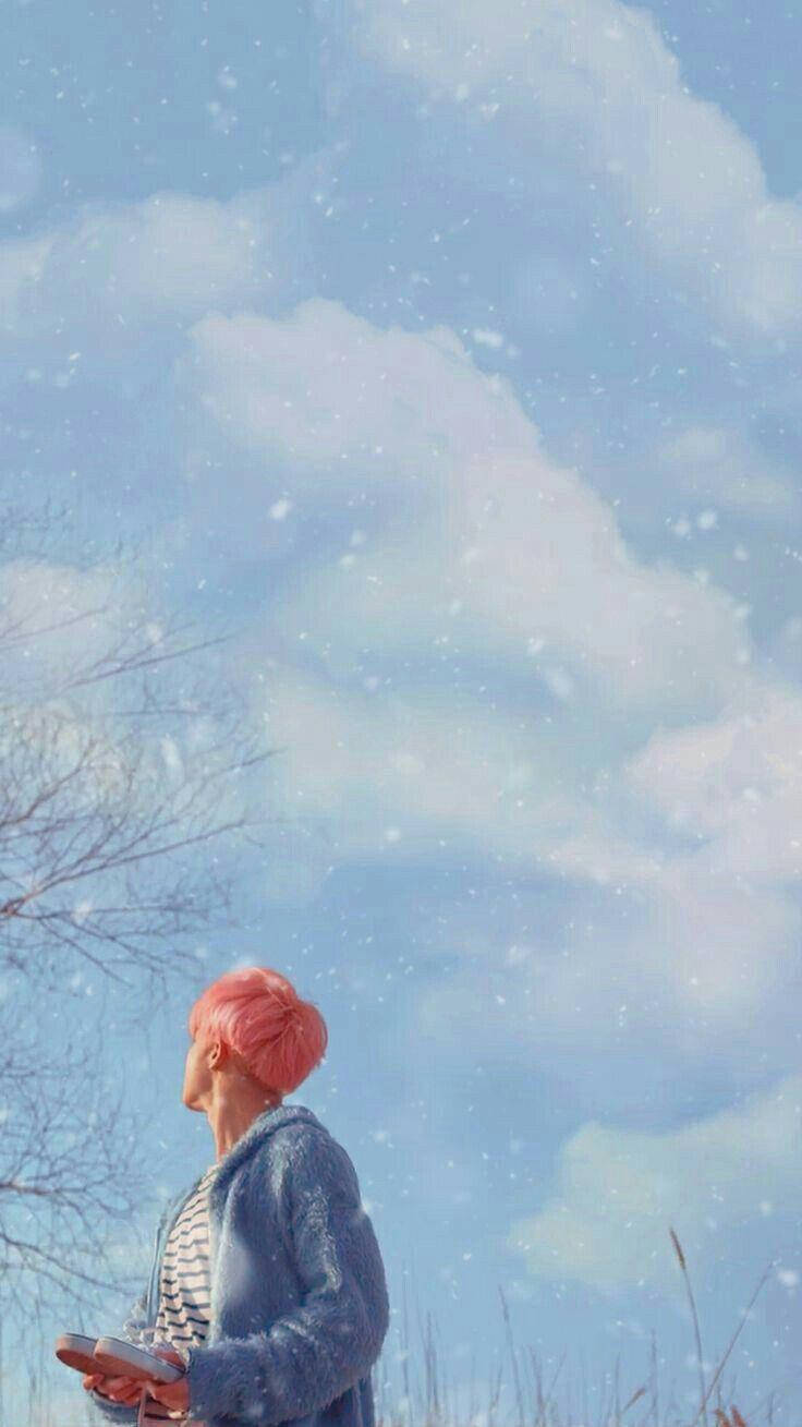 粉紅色頭髮的人站在雪中，藍天之下