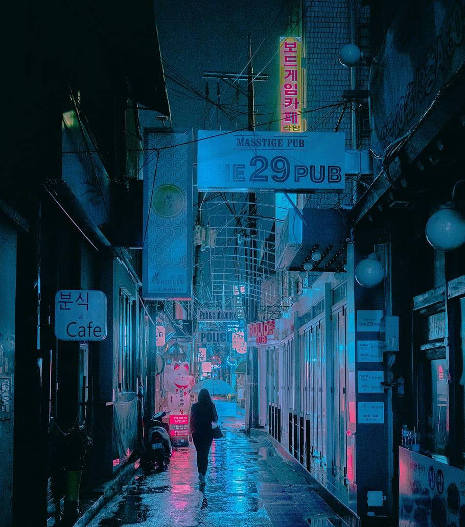 夜晚，一個人在下雨的霓虹燈韓國小巷中獨自行走。