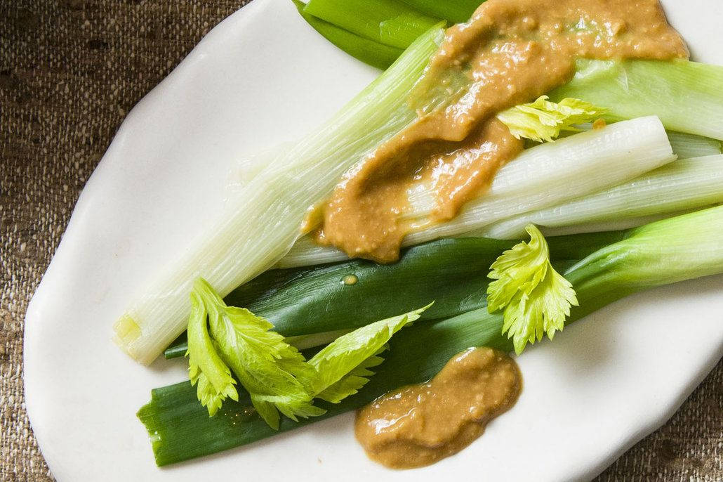 韭蔥蔬菜配芥末醬食譜 壁紙 — 新鮮青蔥和芹菜莖淋上奶油花生醬，放在白色盤子上。