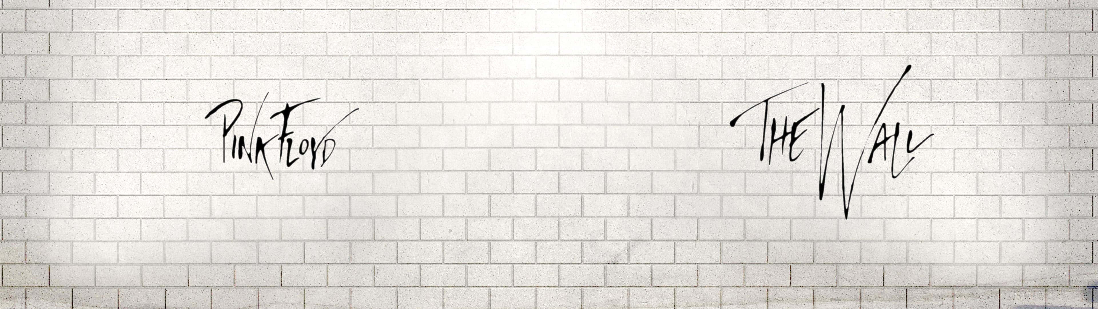 Pink Floyd The Wall 以黑色草書寫在白色磚牆上。