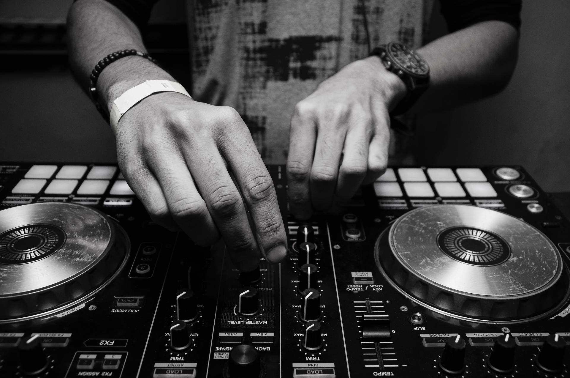 DJ雙手在黑白音樂混音器上調整控制。