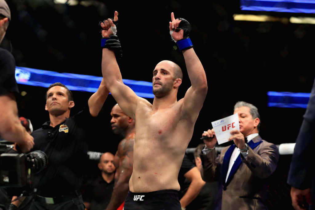 UFC拳手在八角籠中舉臂慶祝勝利。