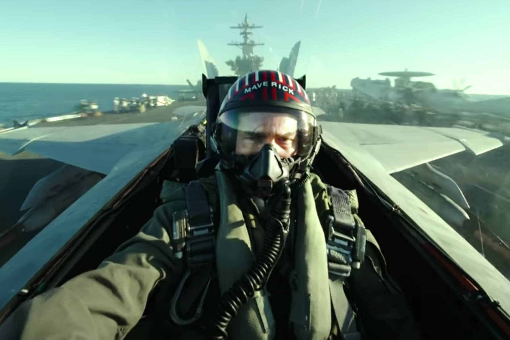戰鬥機駕駛艙中的飛行員，在明亮的日光下可見航空母艦和海洋。