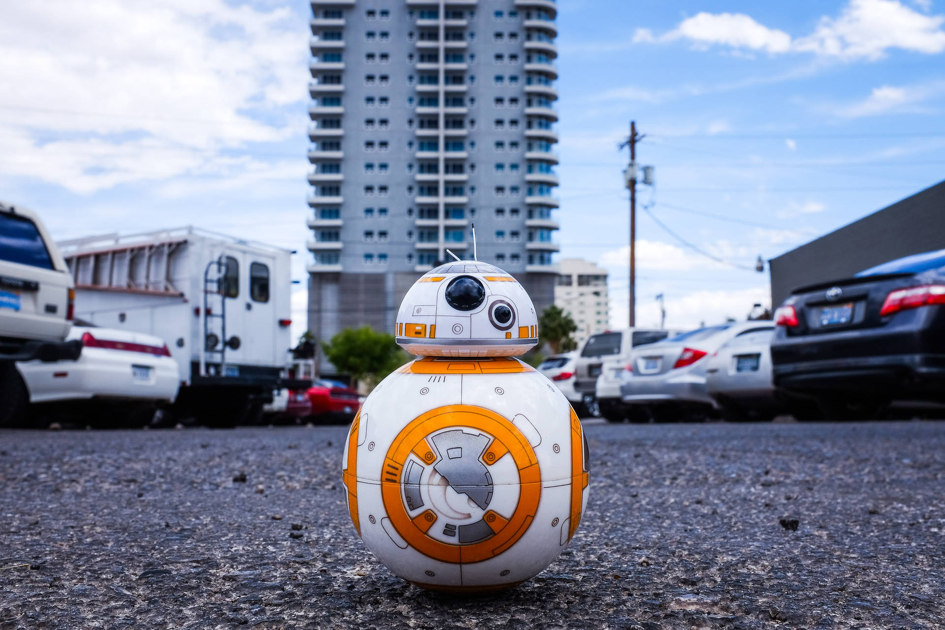 BB-8機械人在城市停車場，有汽車和高樓。