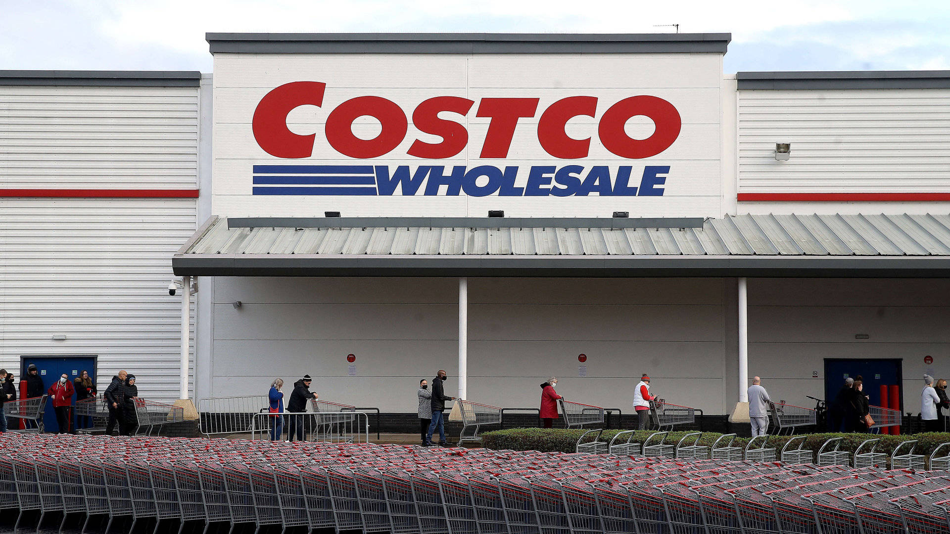 Costco Wholesale 在陰天有購物者和購物車在外面。