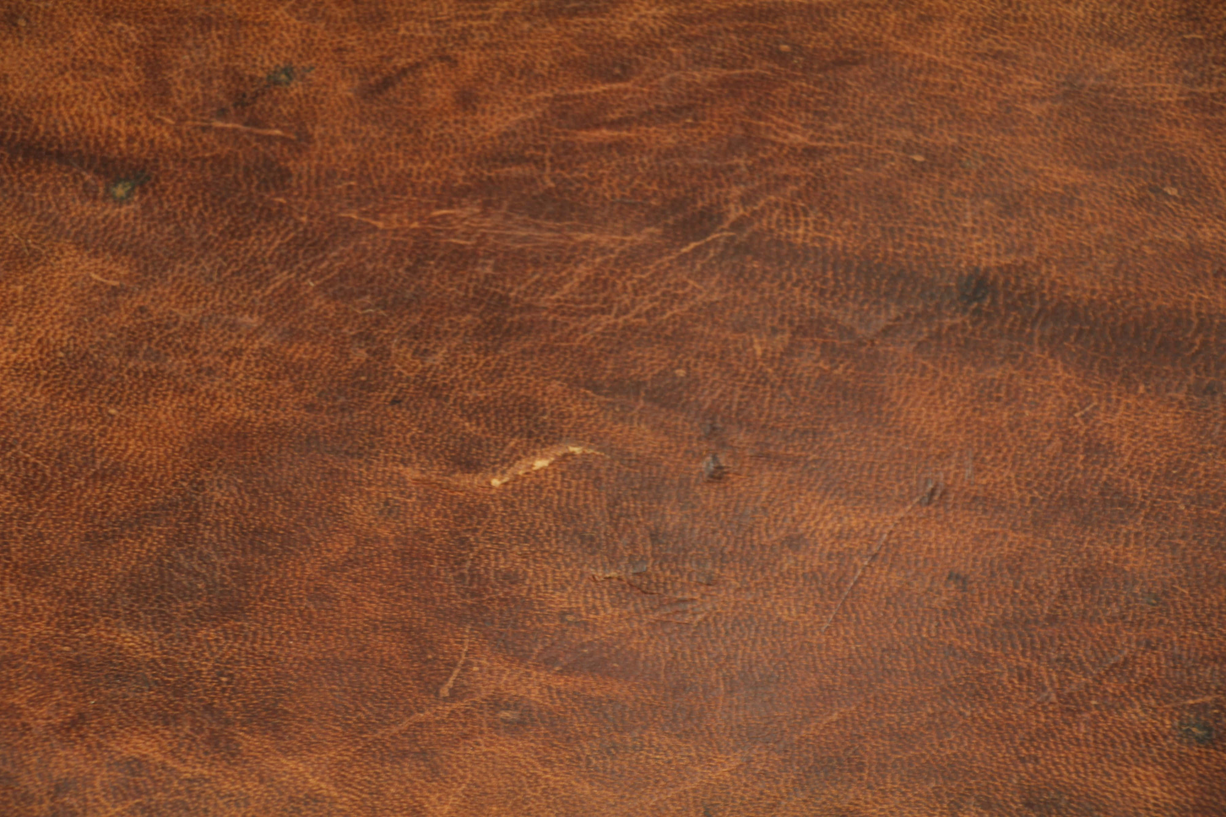 Brown Leather 桌布 壁紙 — 風化棕色皮革的特寫，帶有自然皺褶和散落的深色斑點。