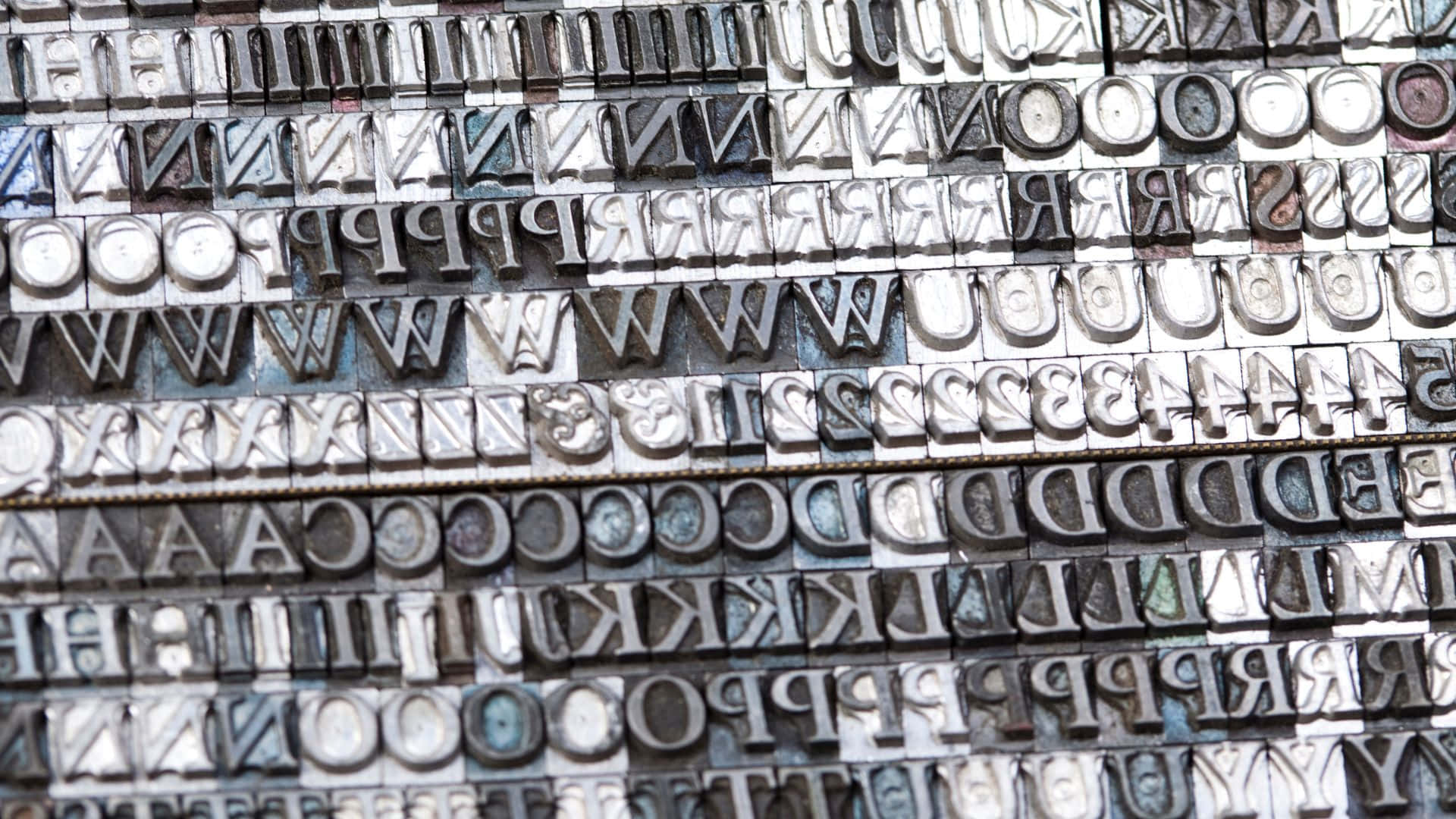 Typography 桌布 壁紙 — 風化金屬活字塊的特寫，整齊排列成行，顯示多種字體和歲月痕跡。
