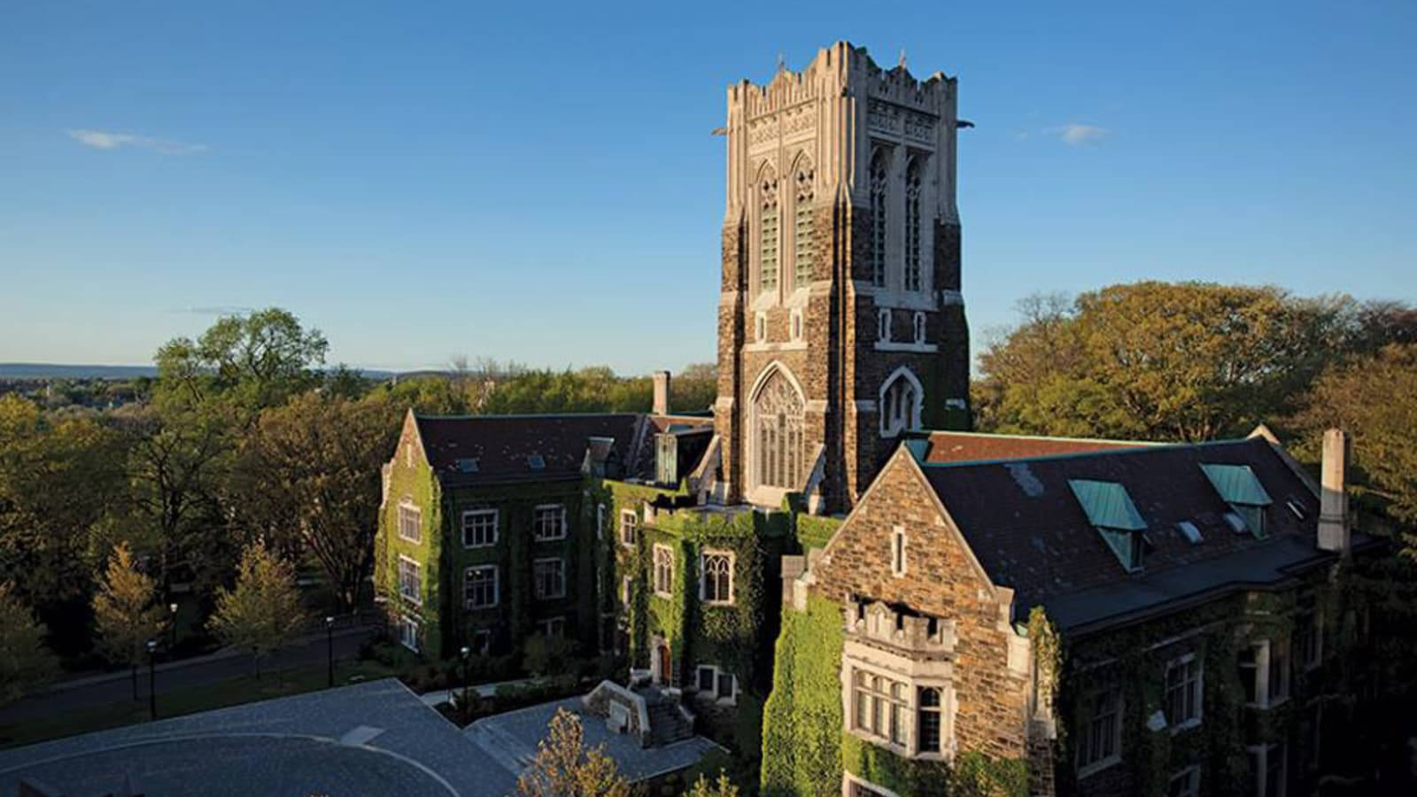 歷史悠久的大學建築，爬滿常春藤的牆壁和高聳的石塔在夕陽下。