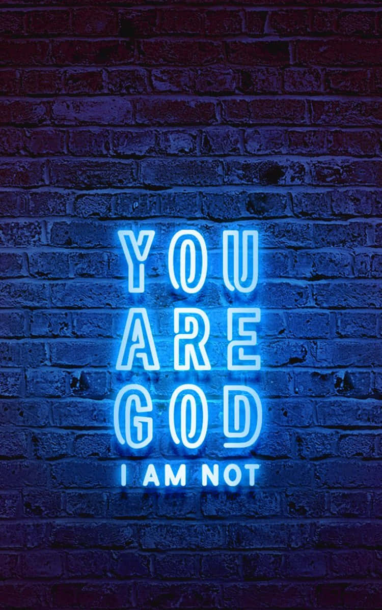 磚牆上的藍色霓虹燈牌顯示 'YOU ARE GOD I AM NOT'