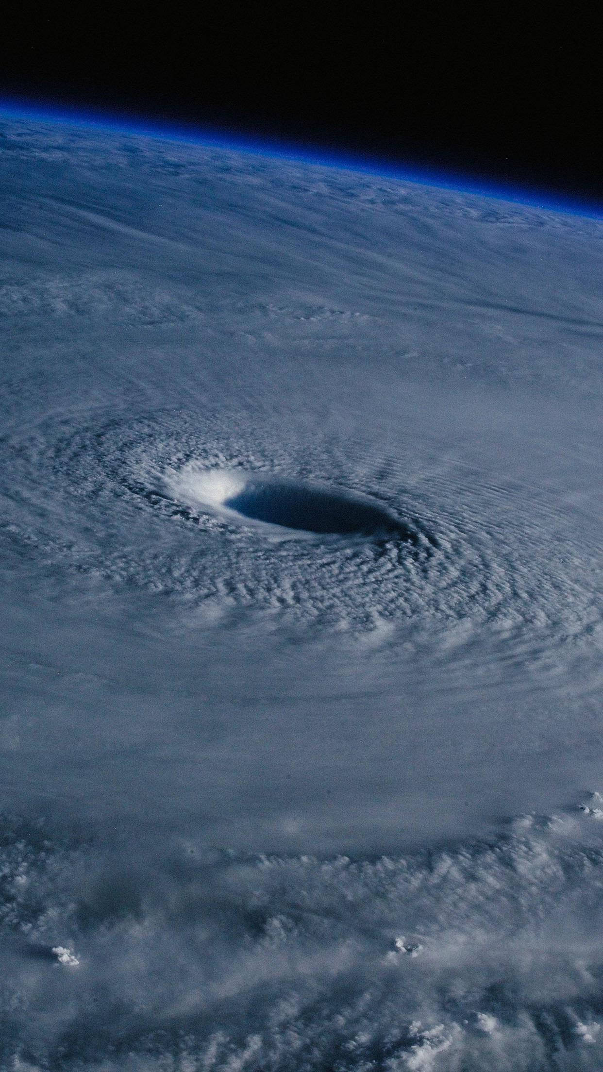 颶風牆雲 壁紙 — 從太空看，一個巨大的颶風在地球的藍色曲線上旋轉，中心有一個黑暗的風眼。