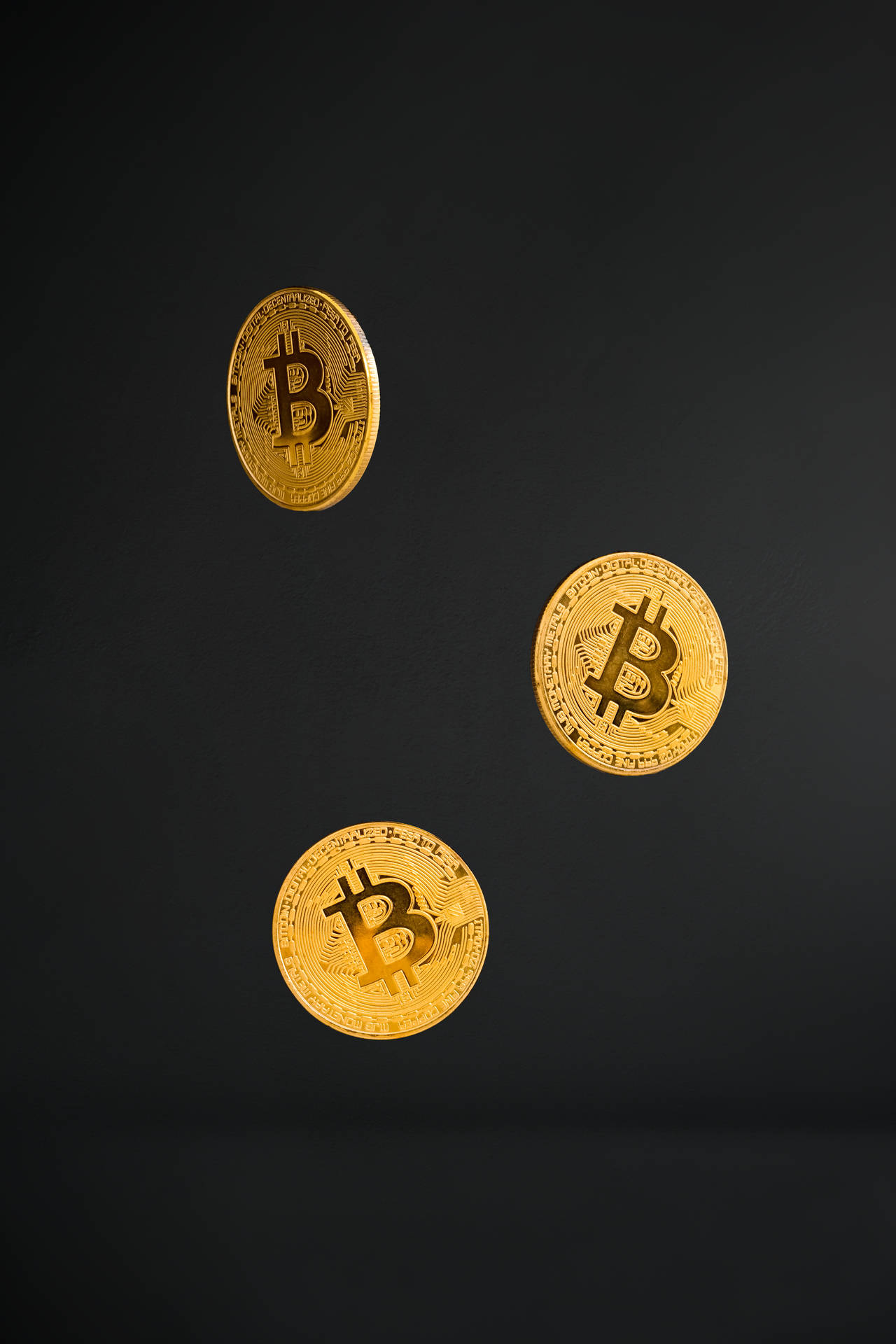 三枚漂浮的金色比特幣，背景為黑色。