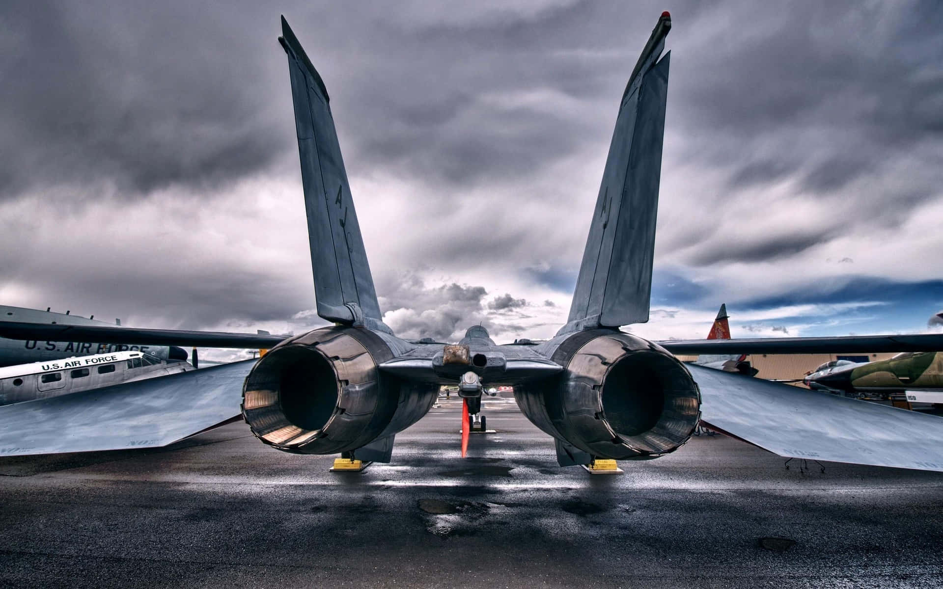 一架軍用戰鬥機在暴風雨天空下的濕滑停機坪上。