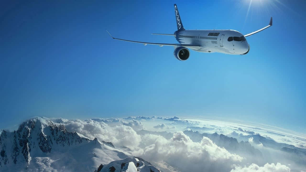 飛機在積雪的山脈和雲層之上飛行，天空湛藍明亮。