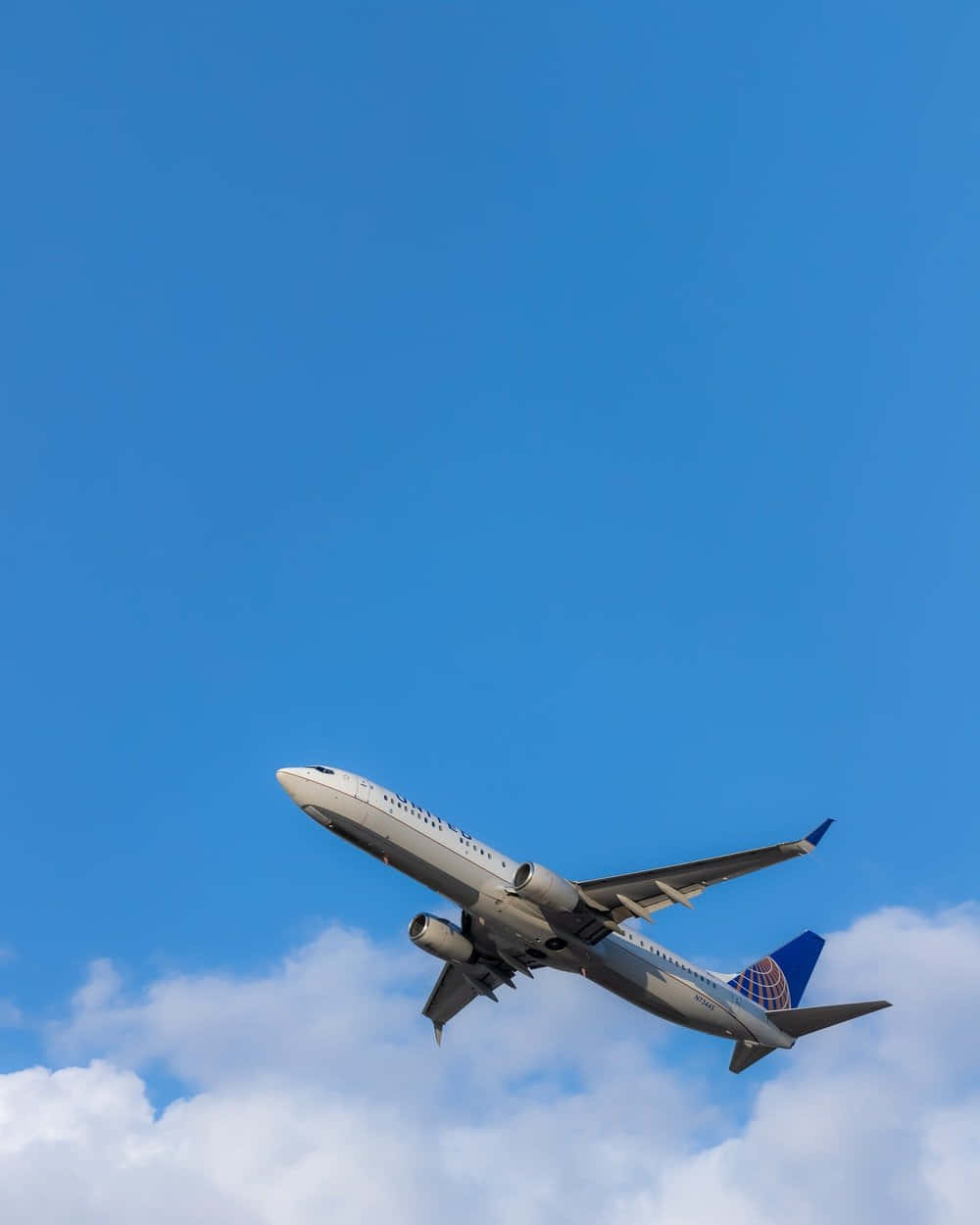 聯合航空噴射機在藍天中攀升，伴有白雲