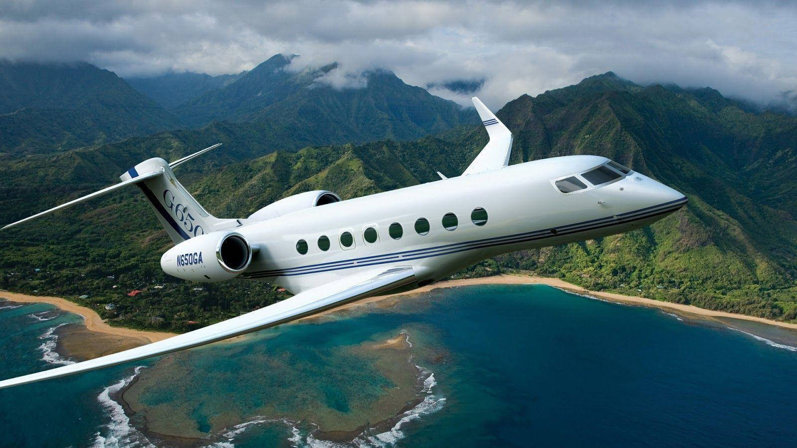 飛機 Gulfstream G650 模型 壁紙 — 一架時尚的白色私人飛機在陰天低飛過碧綠的海水和茂密的綠色山脈。