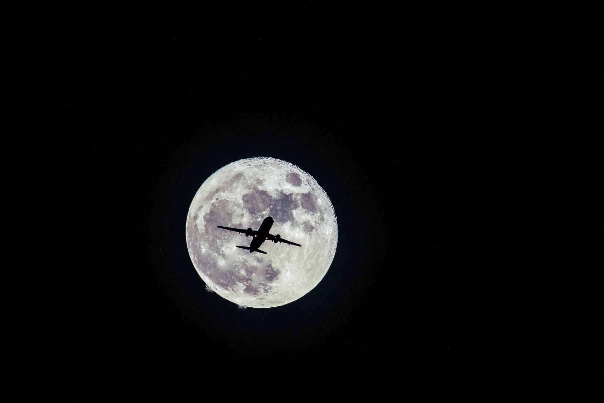 飛機在夜間飛過滿月前。