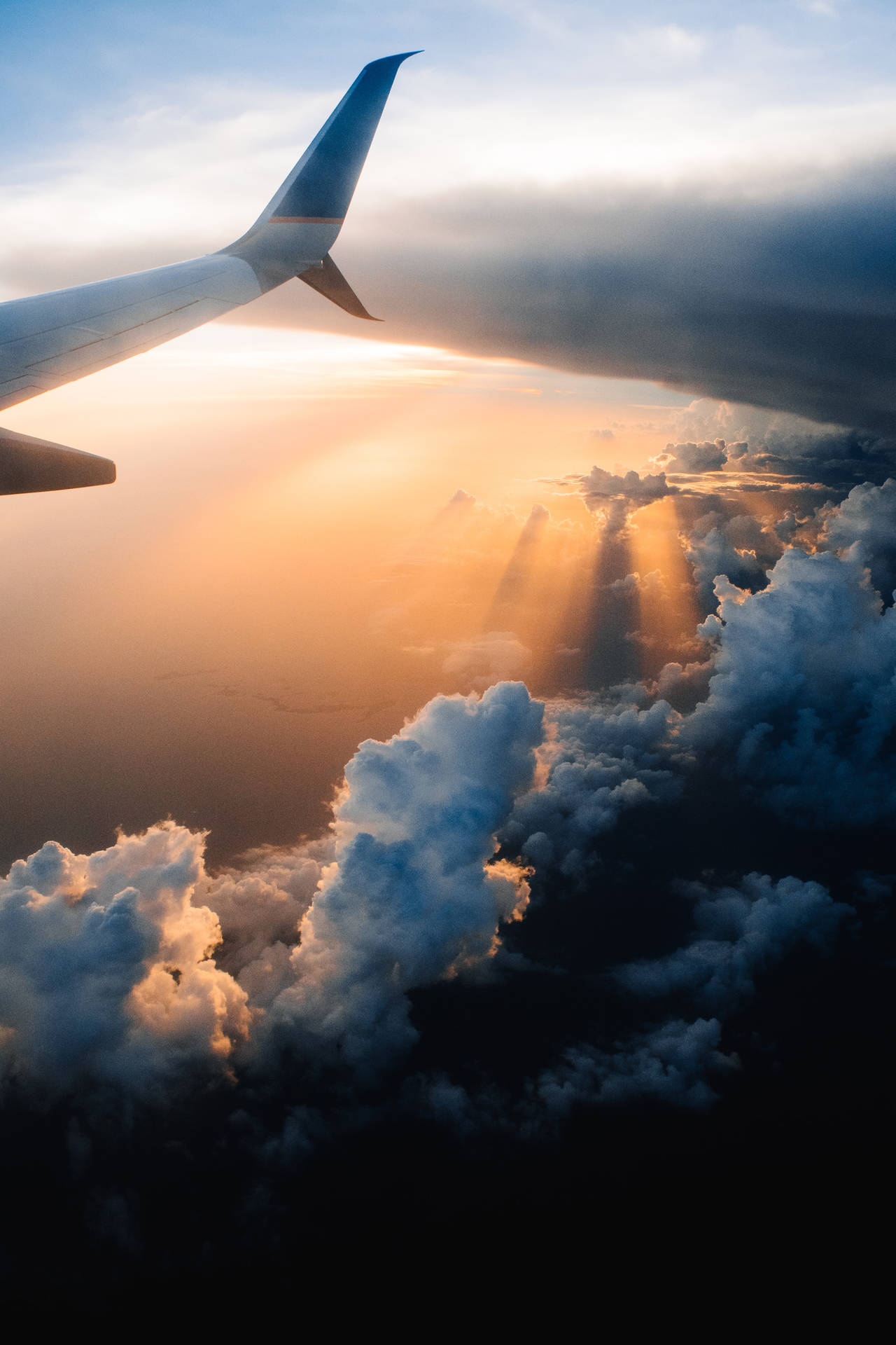 飛機機翼視角，夕陽光芒穿透雲層。