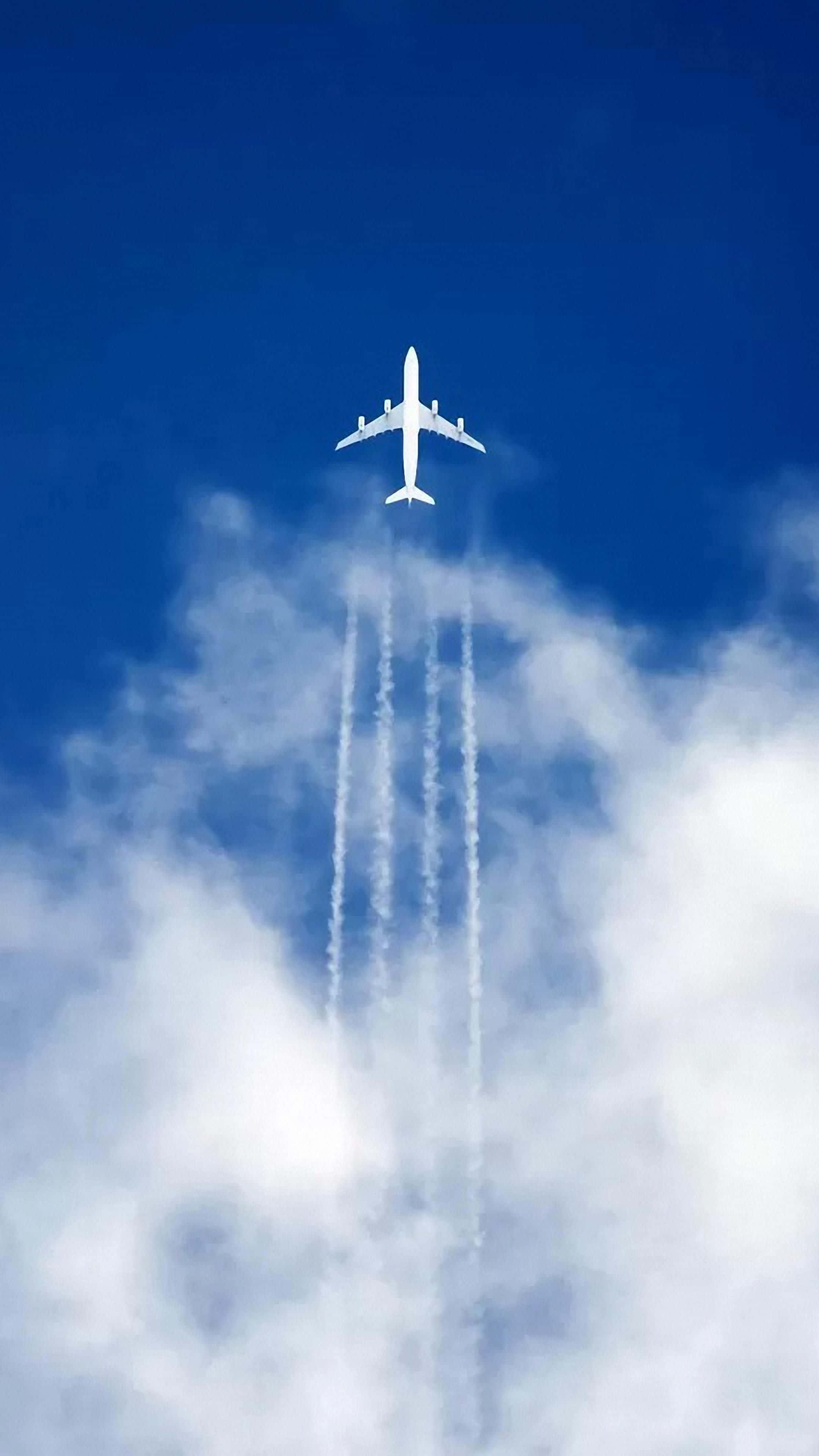 飛機留下四道煙跡安卓飛機壁紙 壁紙 — 一架白色客機在鮮豔的藍天中翱翔，攀升到蓬鬆的白雲之上，留下四條清晰的凝結尾跡。