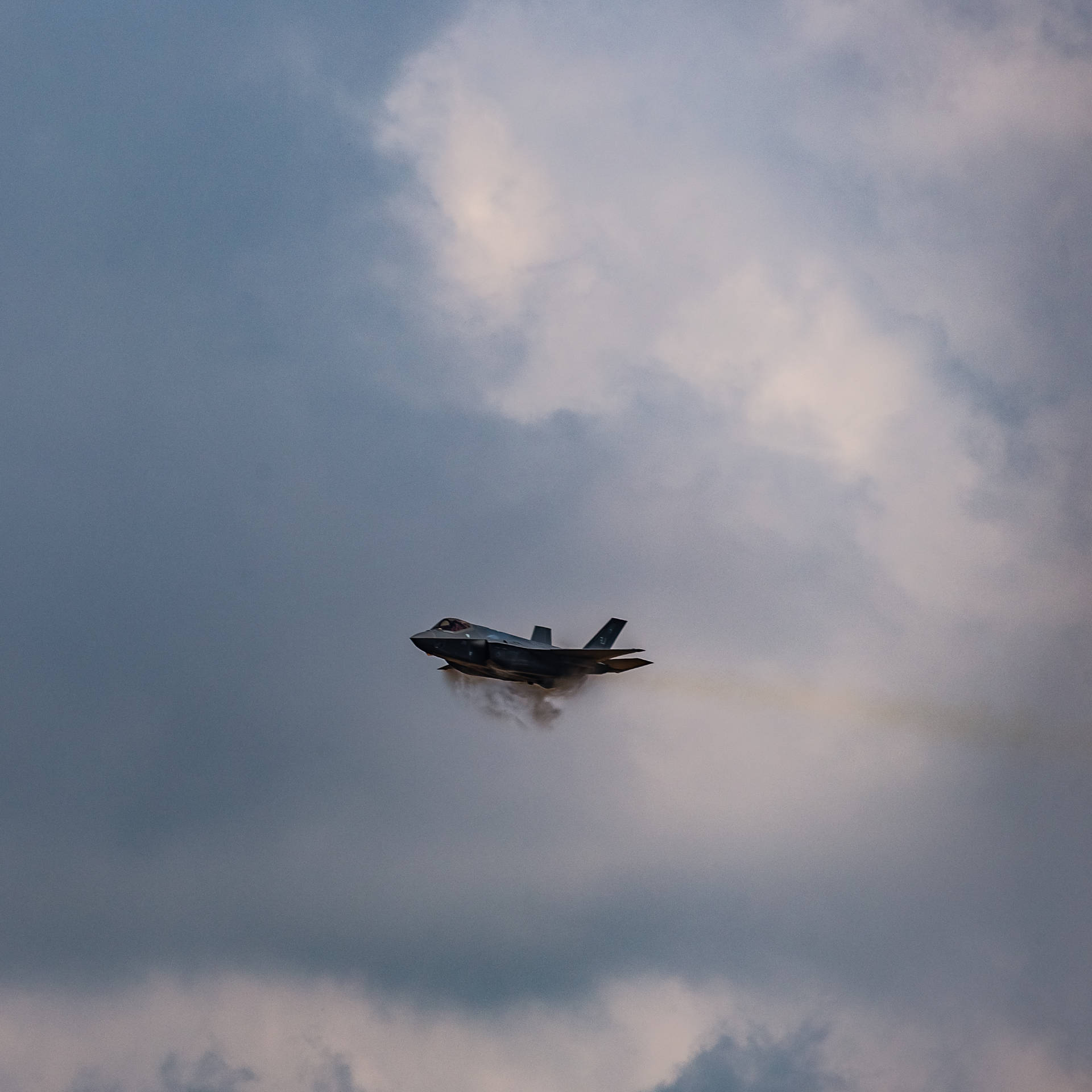 戰鬥機在多雲天空中飛行留下煙霧痕跡
