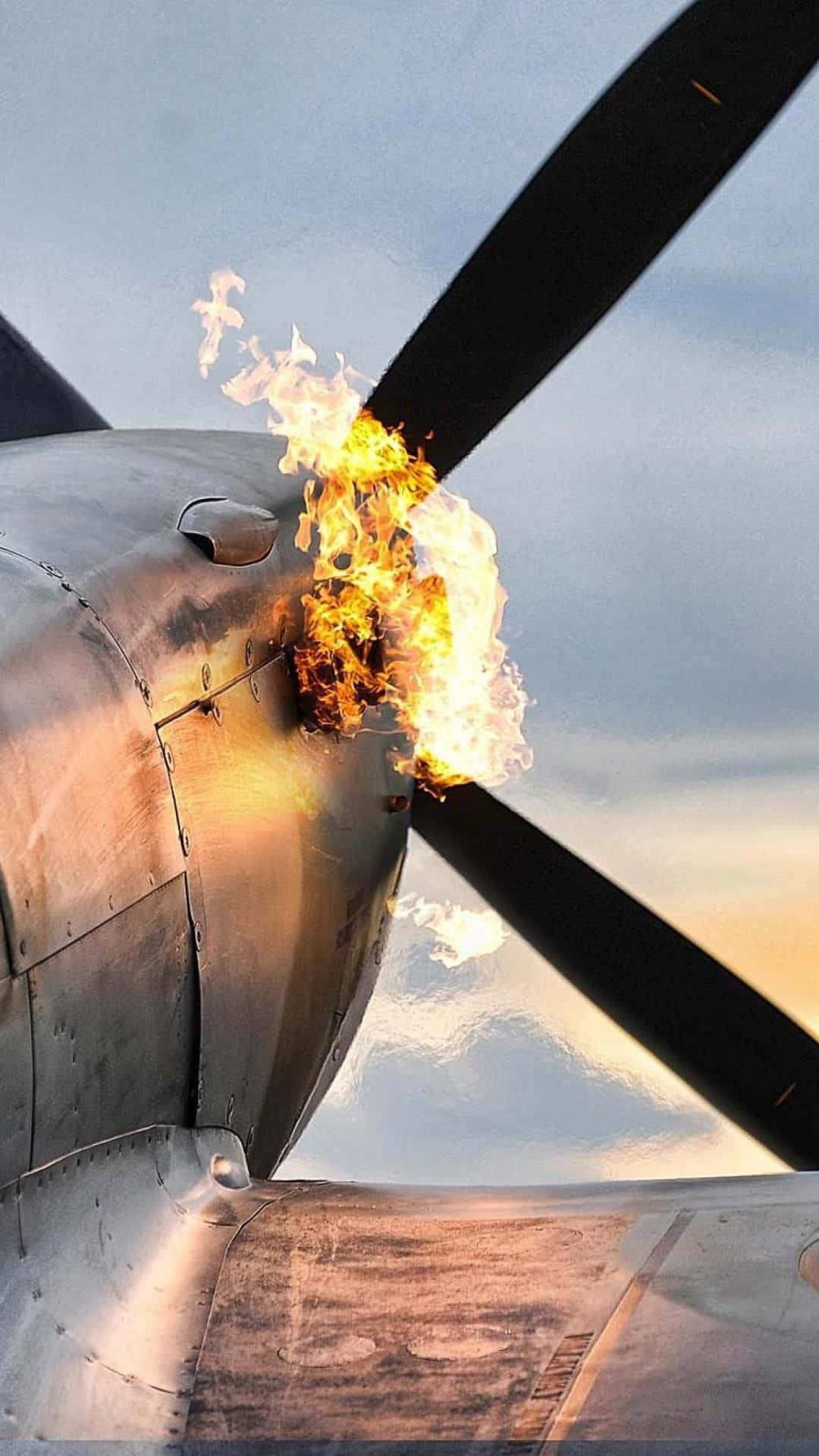 飛機穿過蓬鬆白雲的空中視角 壁紙 — 一架復古飛機的螺旋槳在柔和的暮色天空中爆發出明亮的火焰。