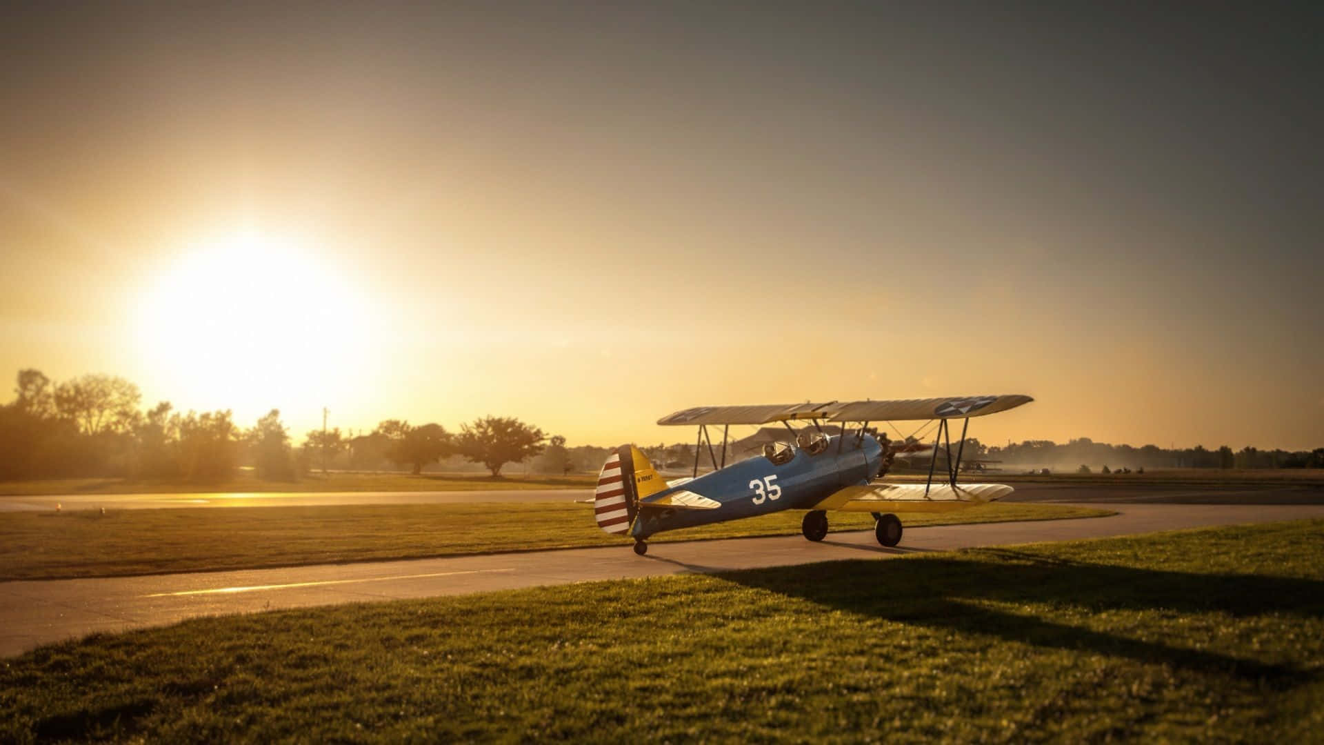 復古雙翼飛機在金色夕陽下的跑道上投下長影