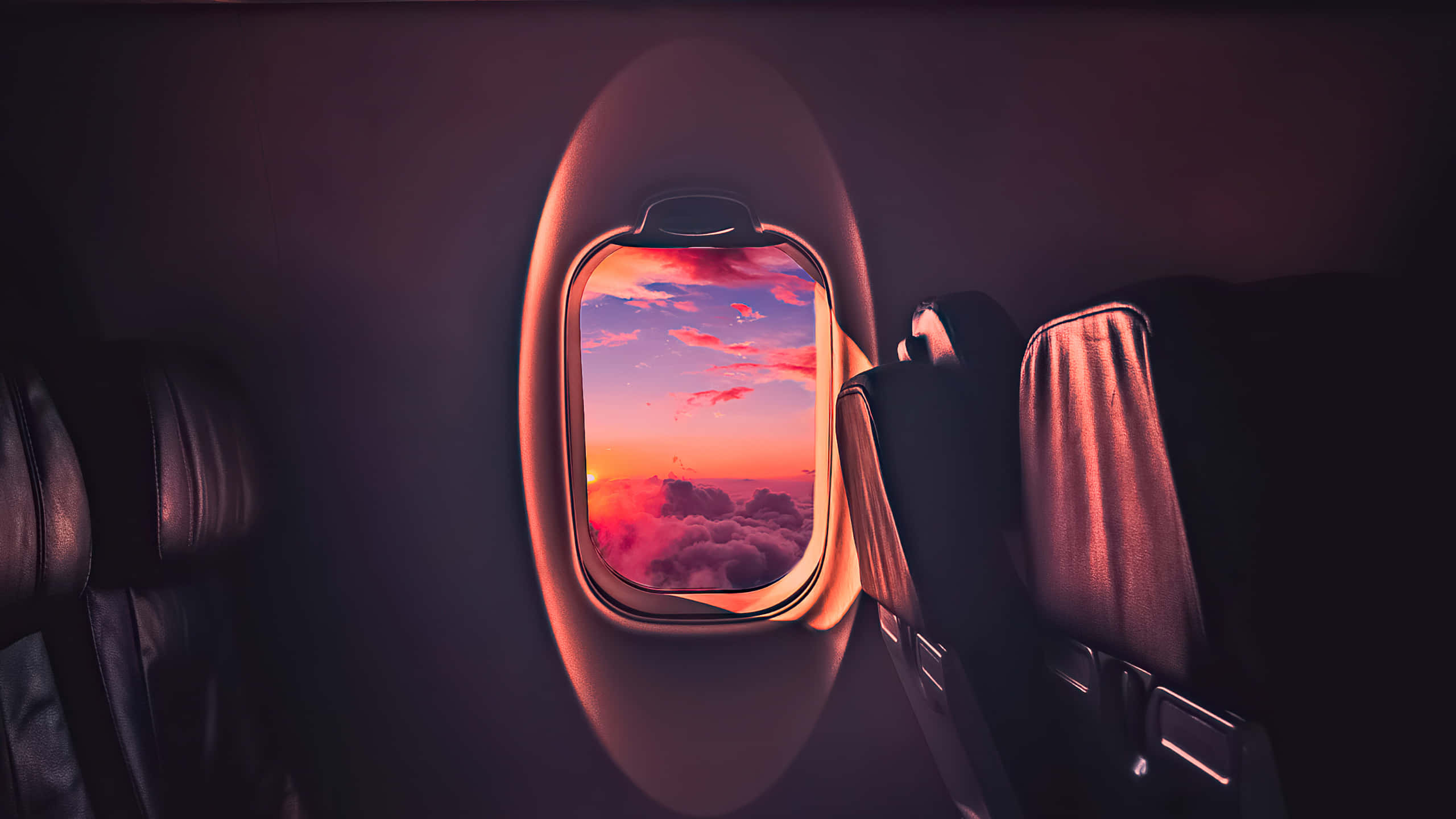 飛機窗戶 1440p AMOLED 背景 壁紙 — 從昏暗機艙內看到的飛機窗外景觀，蓬鬆雲朵上 vibrant 粉紅與橙色日落。