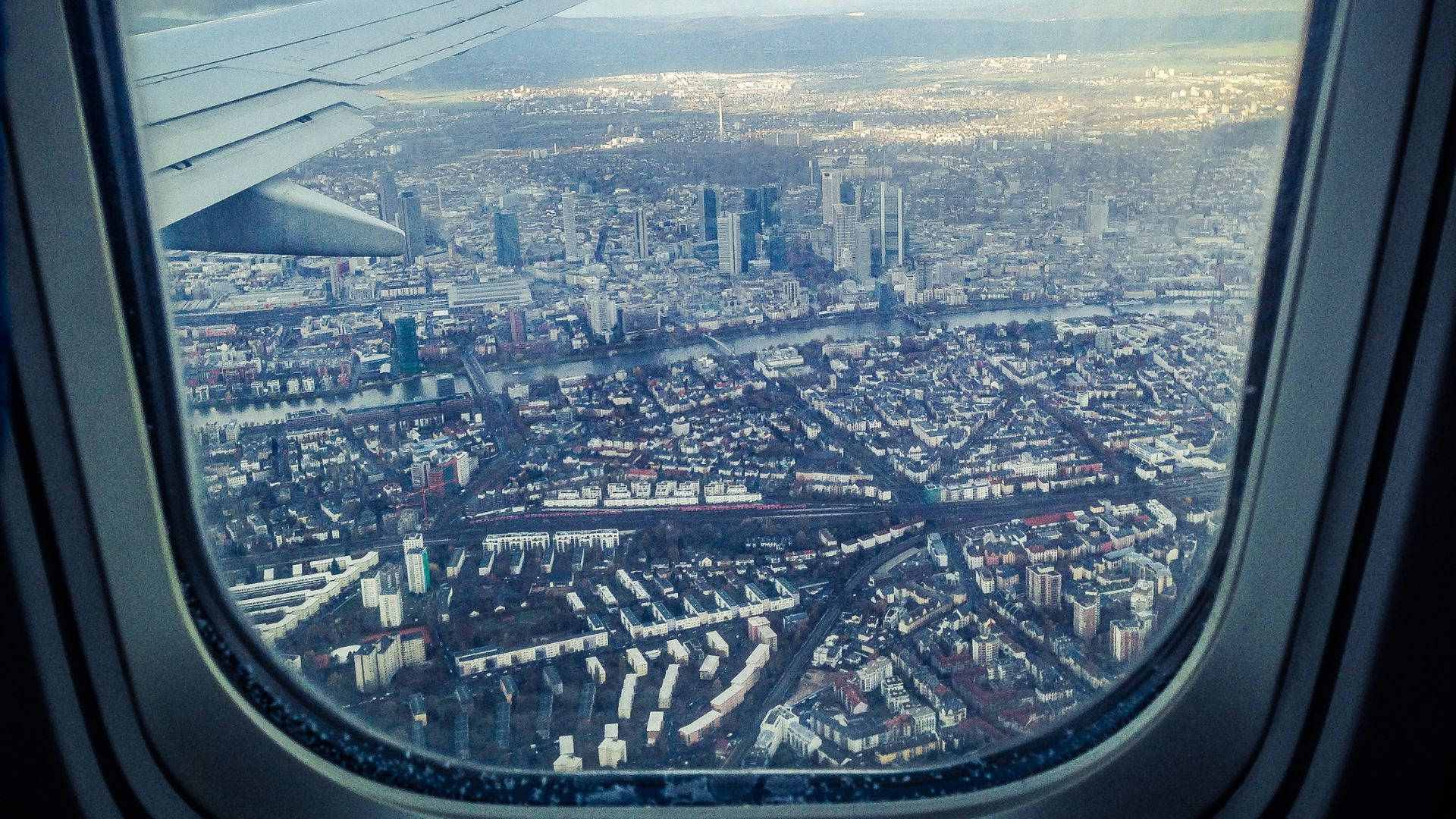 飛機窗戶旅行城市景觀 壁紙 — 從飛機窗戶看到廣闊城市景觀的鳥瞰圖，機翼可見。