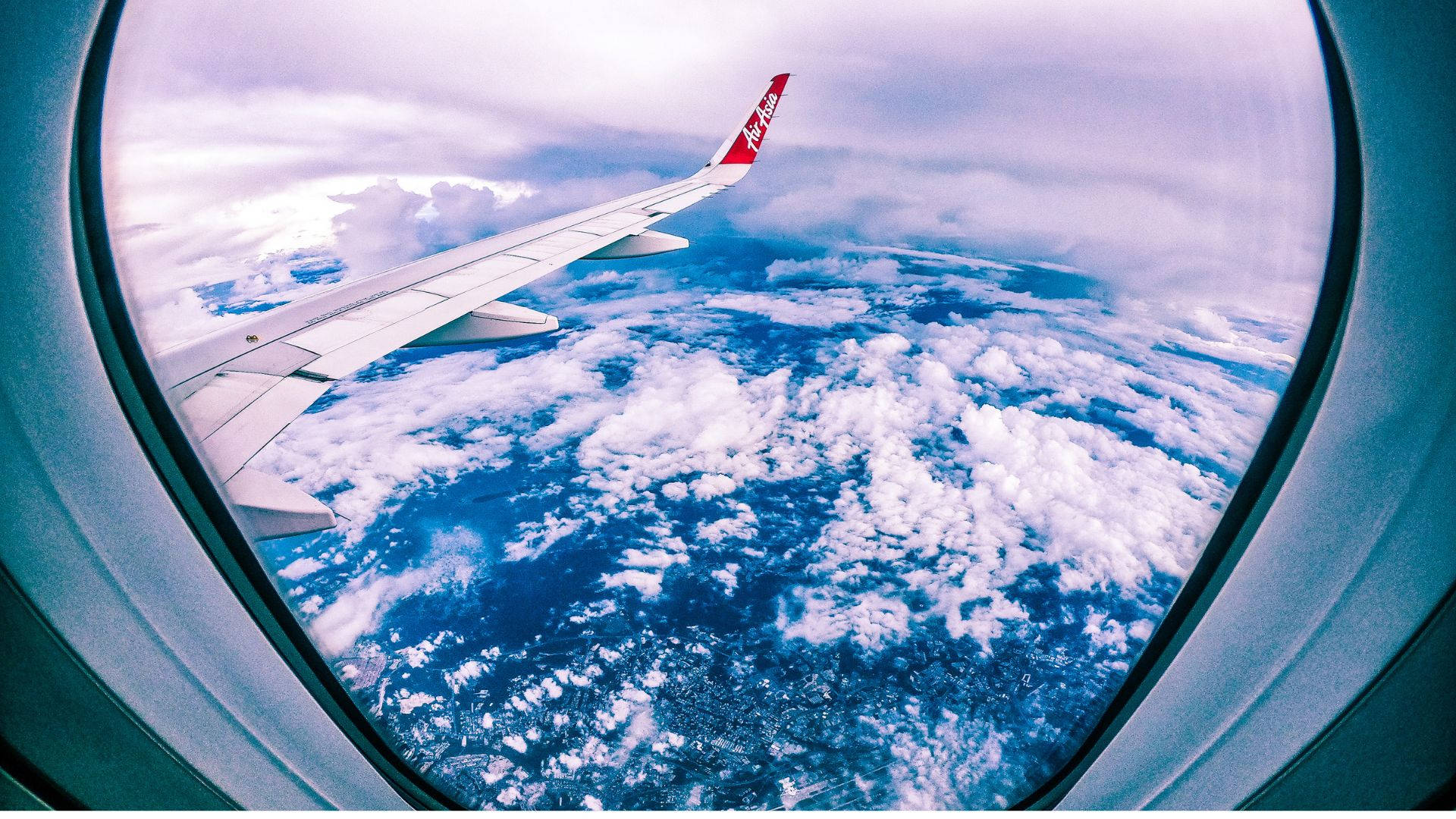 飛機窗戶旅行魚眼雲朵 壁紙 — 從飛機窗戶看到的飛機機翼，俯瞰下方蓬鬆的白雲和藍色海洋。