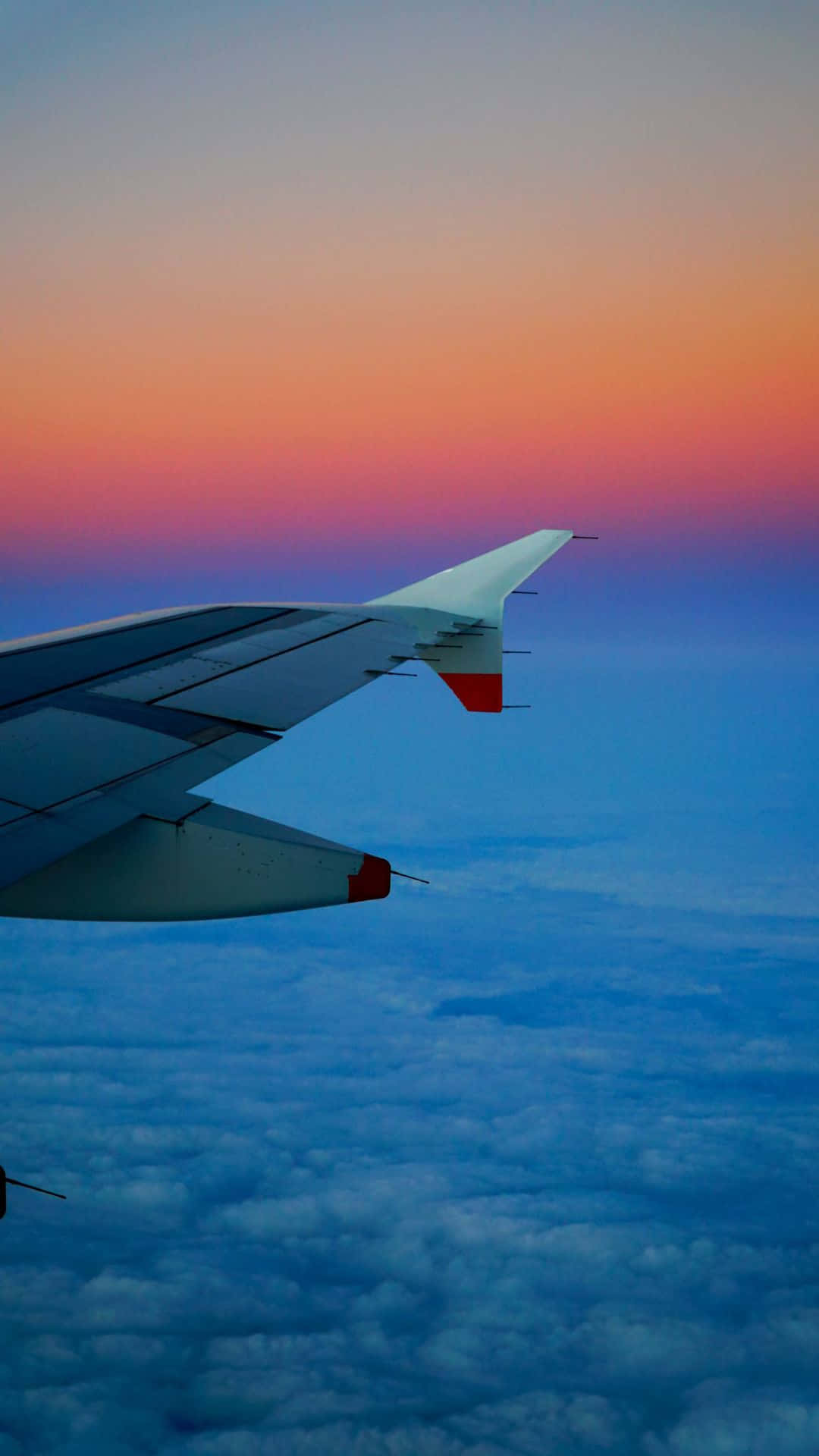 日落時分飛機機翼在雲層上空翱翔