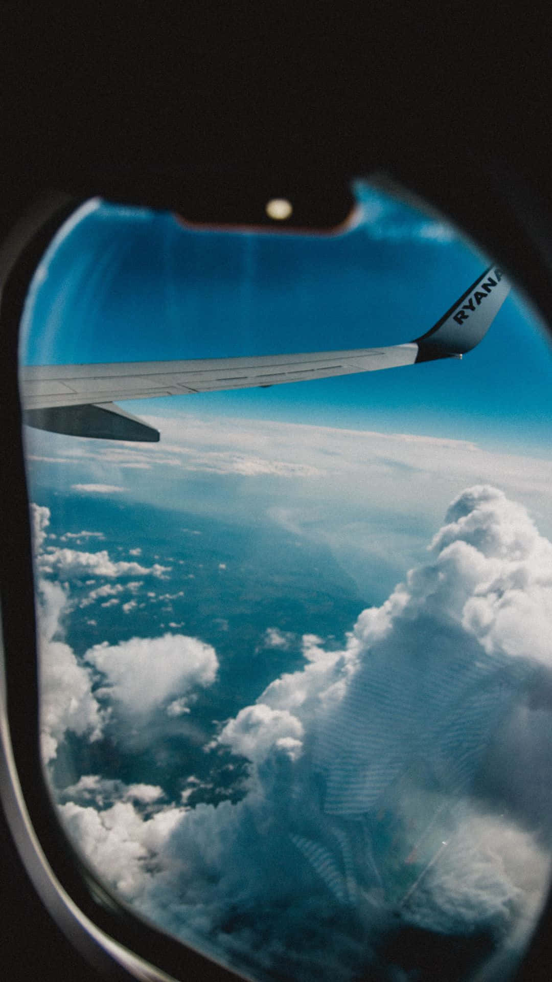 從飛機窗戶看到的景色，顯示機翼和下方的雲