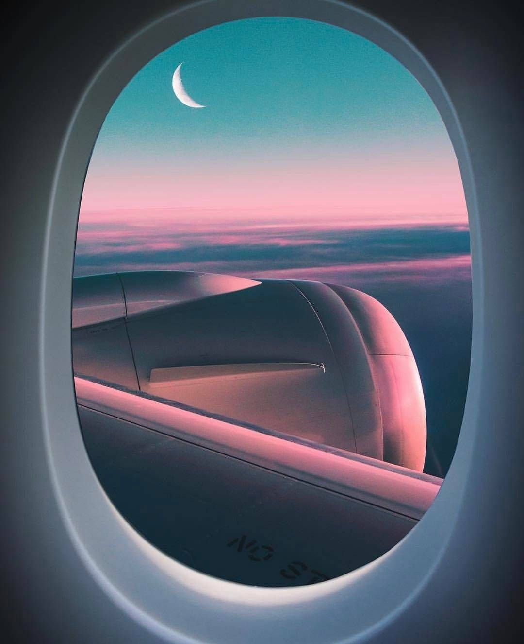 飛機窗景旅行月相 壁紙 — 從飛機窗戶看到的寧靜景色，粉紅色和藍綠色雲層上方有一彎新月，機翼在下方。