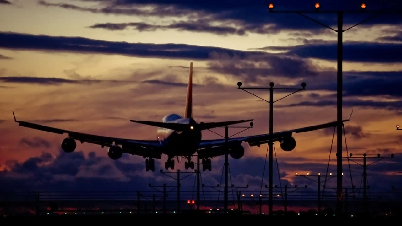 飛機翱翔在星期一早晨的雲層中 壁紙 — 一架大型飛機在橙紫雲彩的戲劇性暮色天空中呈現剪影。