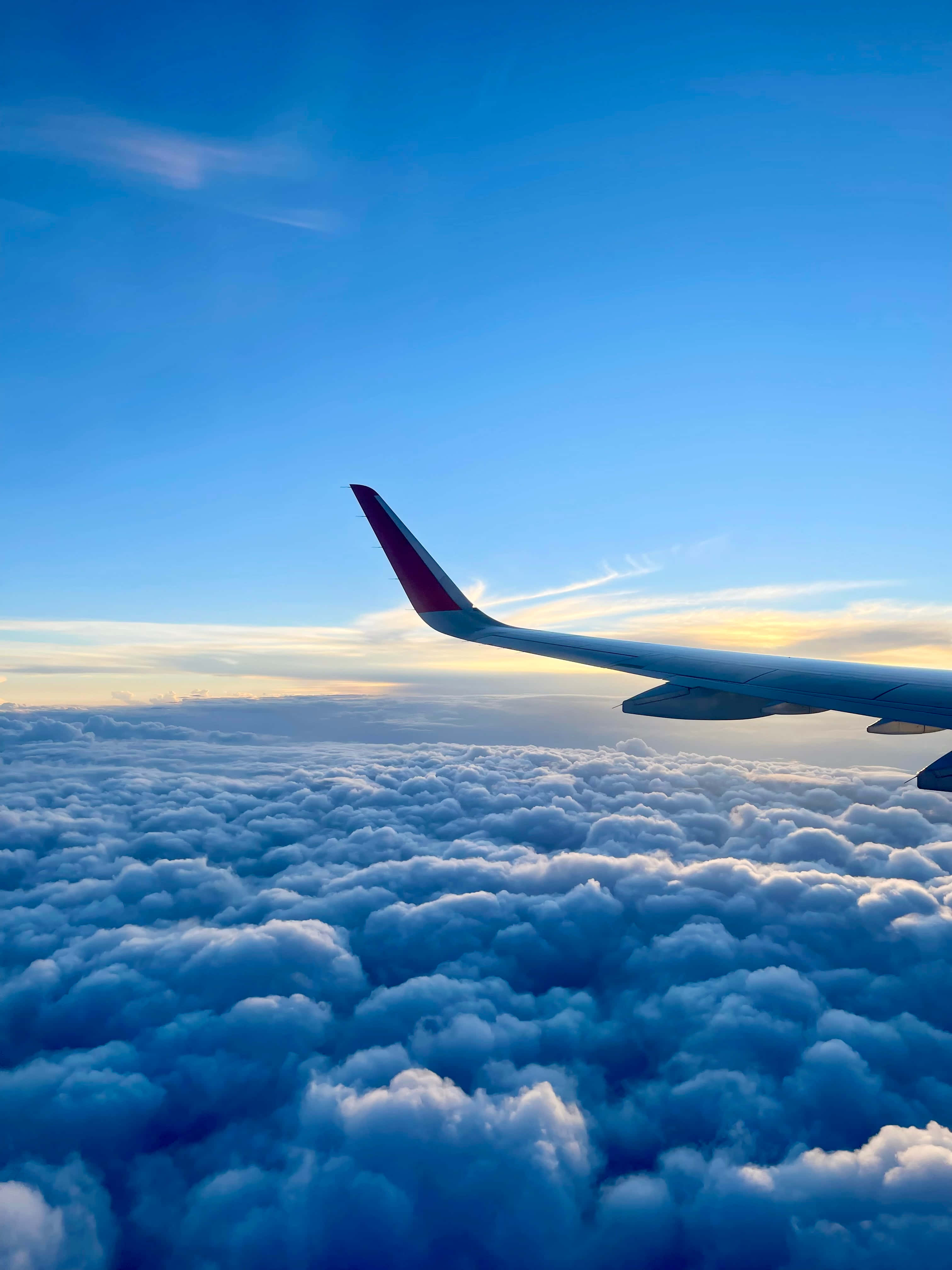 飛機翼掠過雲層 Android 飛機背景 壁紙 — 飛機翼在金色日出下，於清澈藍天中無盡的棉花雲上滑翔。