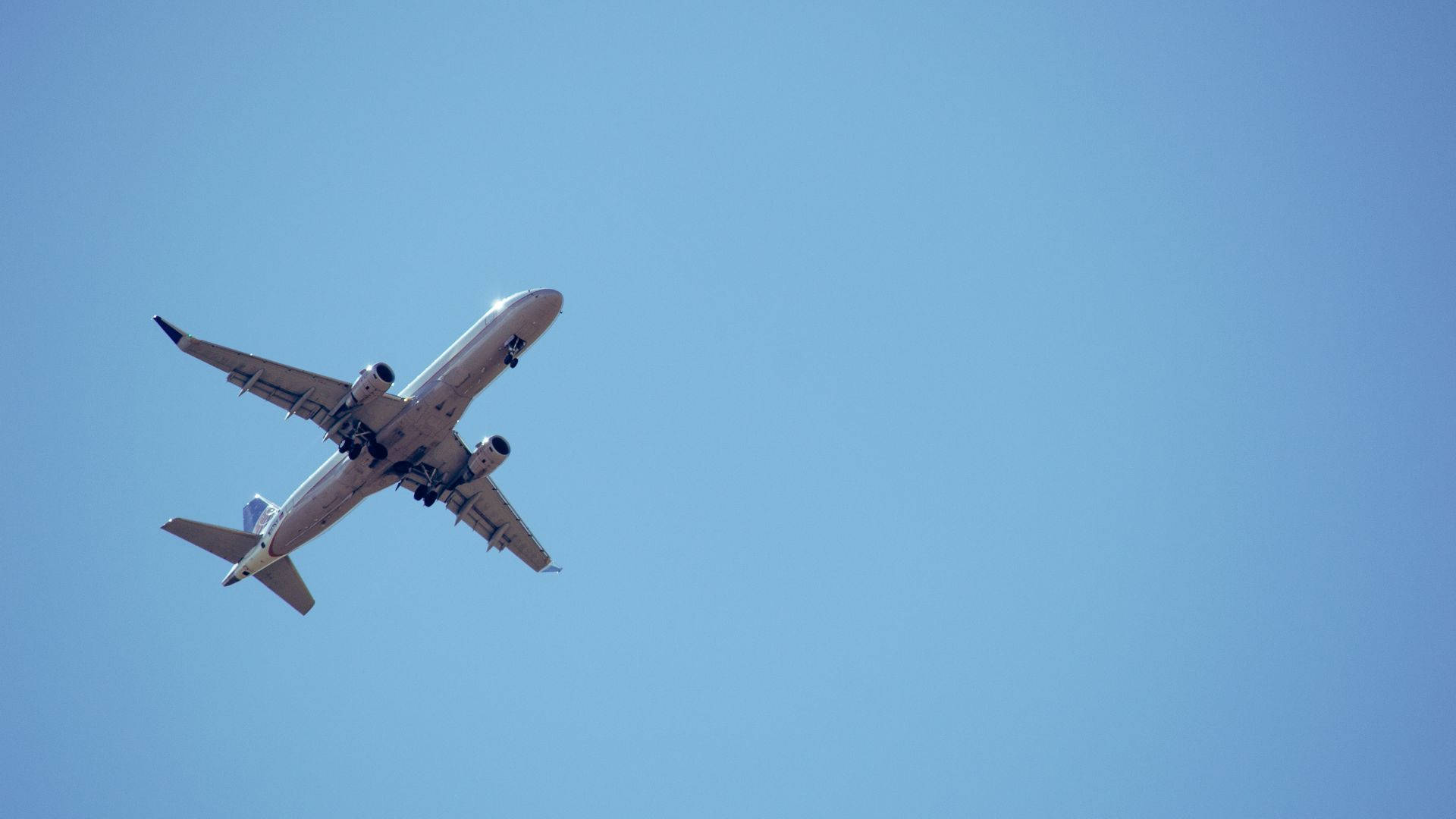 飛機與晴朗天空 壁紙 — 一架白色客機在廣闊清澈的藍天中翱翔，起落架已放下。