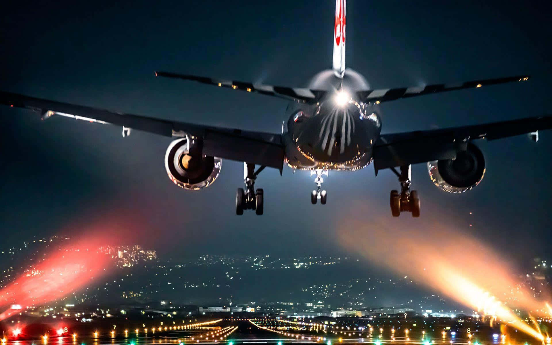 飛機在夜間降落在燈火通明的跑道和城市上空。