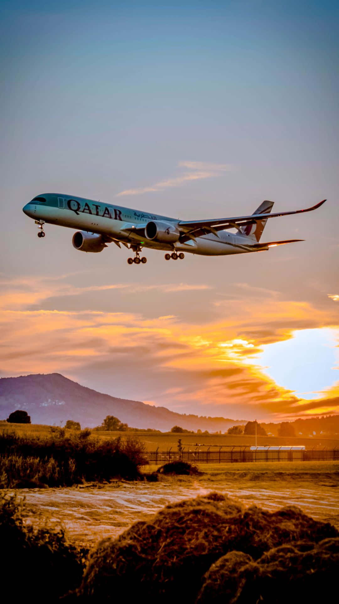卡塔爾航空飛機在日落時分降落在山丘和田野上