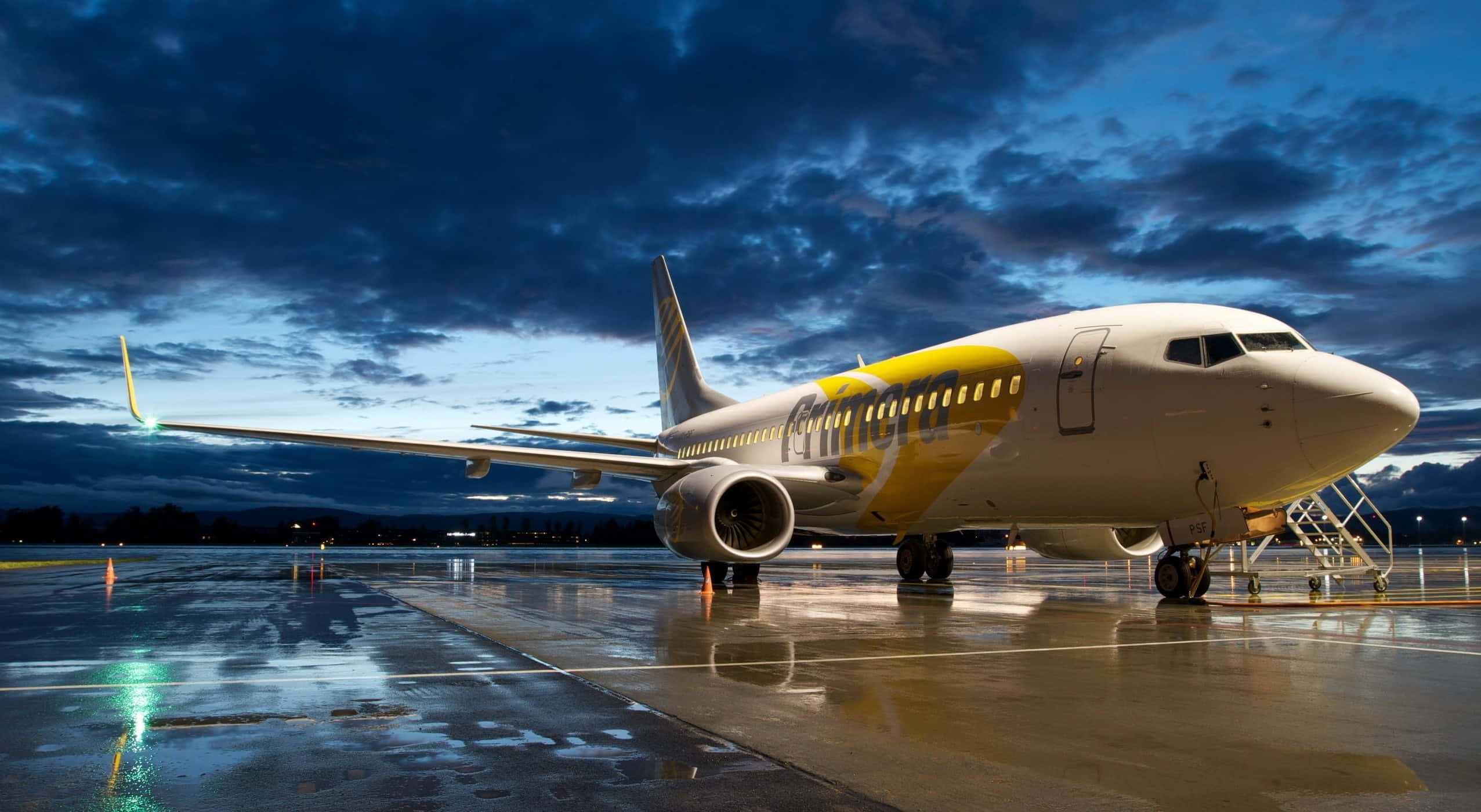 飛機飛越美麗晴朗藍天 壁紙 — 一架瑞安航空飛機停在濕滑的停機坪上，戲劇性的暮色天空下，雲朵倒映在水坑中。