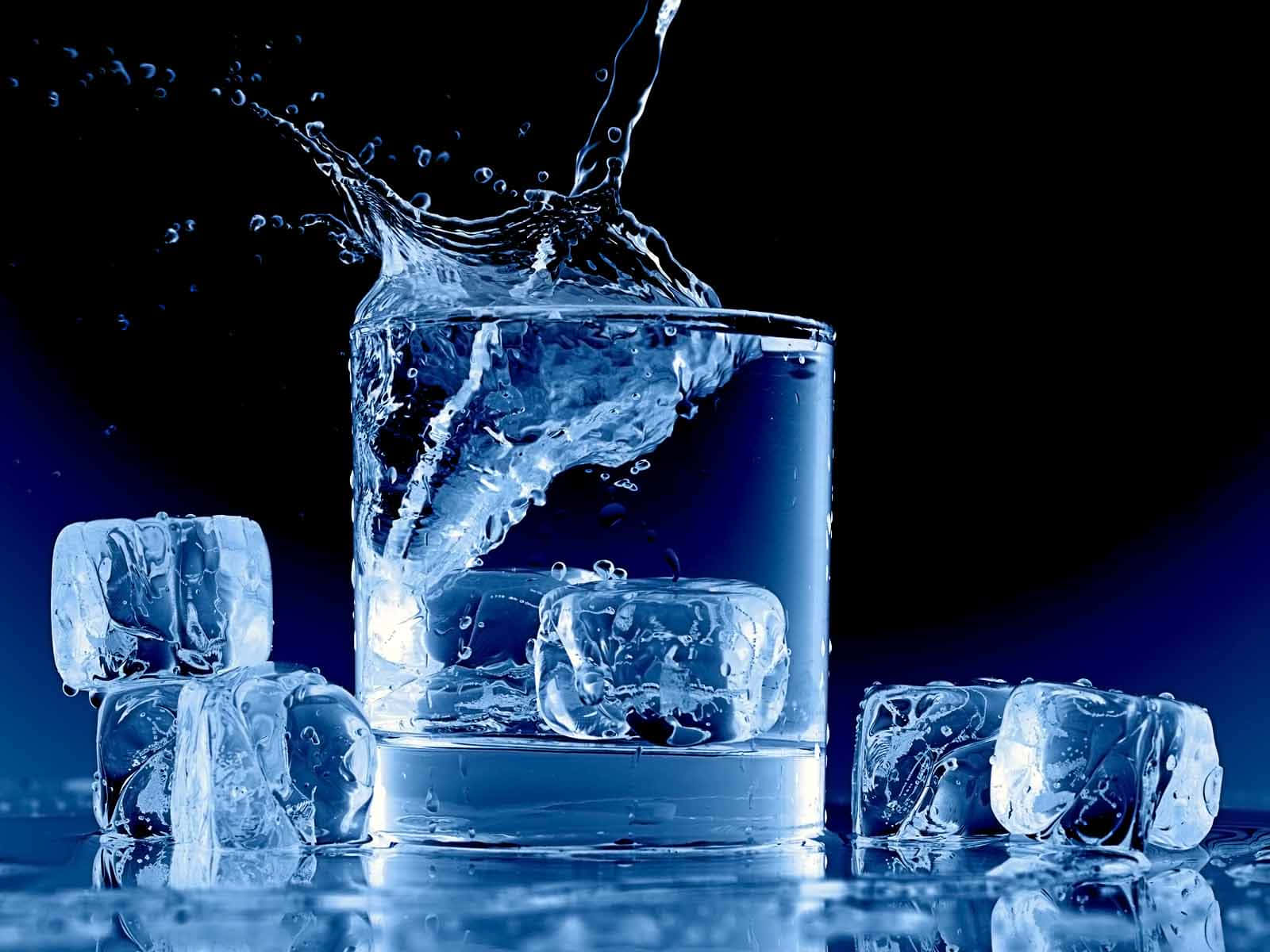 一杯冰水，水花在半空中被捕捉，落在反光表面上。
