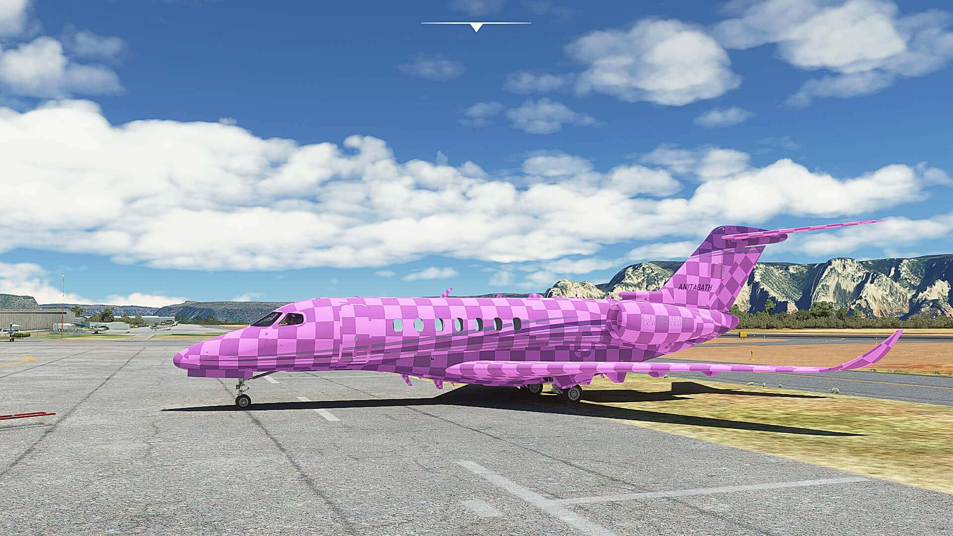 粉紅色格子私人飛機停在機場停機坪上，背景有山脈和雲朵。