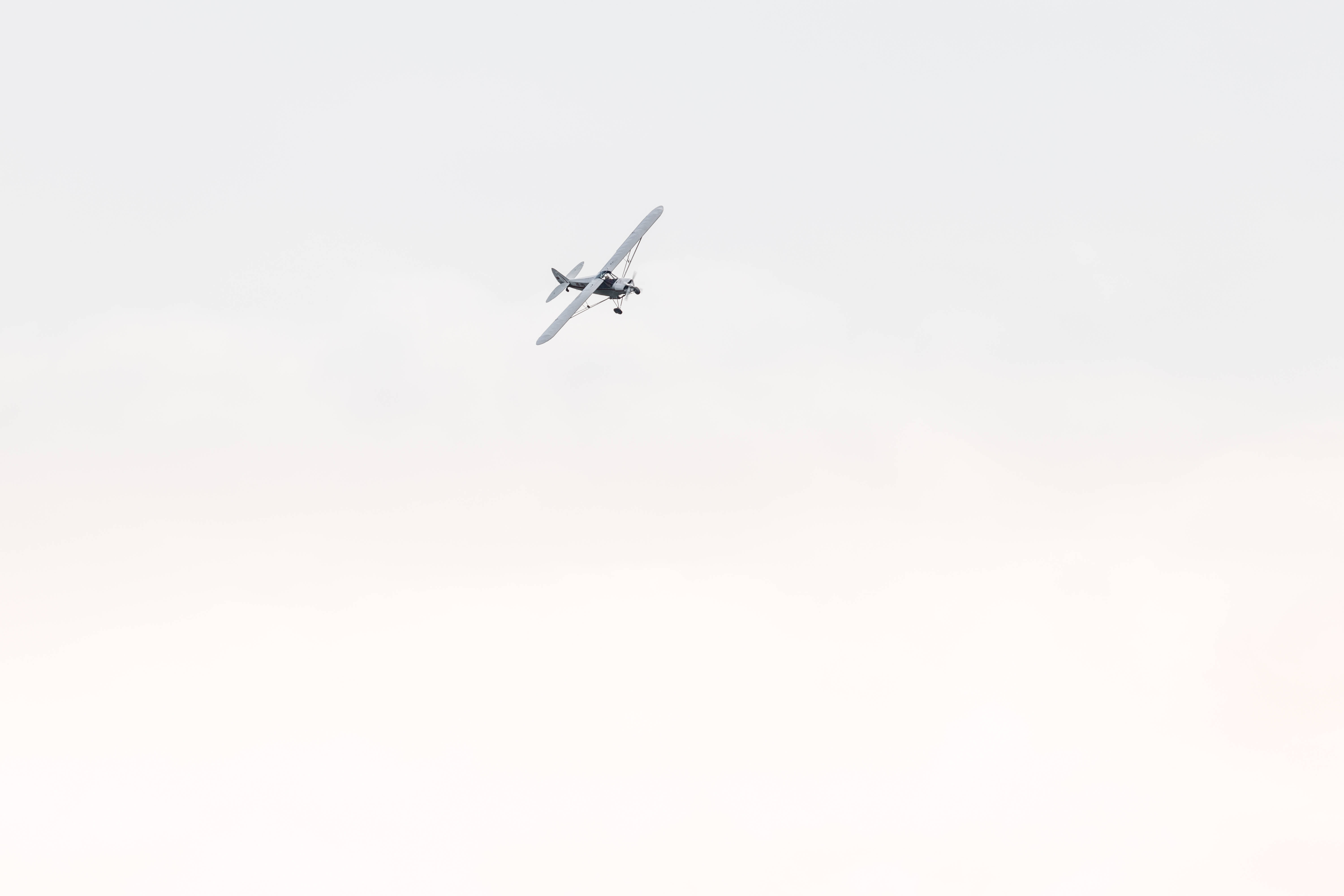飛行中的小型飛機 壁紙 — 一架小型單引擎飛機獨自翱翔在廣闊蒼白、雲層柔軟的天空中。